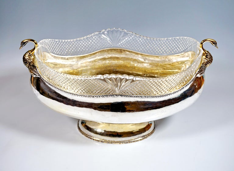 Solid silver vessel in an oval basic shape with a wide, bulbous body, stepped, arched, oval base, smooth, hammered surfaces with palmette rims on the upper, curved edge of the vessel, as well as on the lower edge of the base, two dainty swan busts