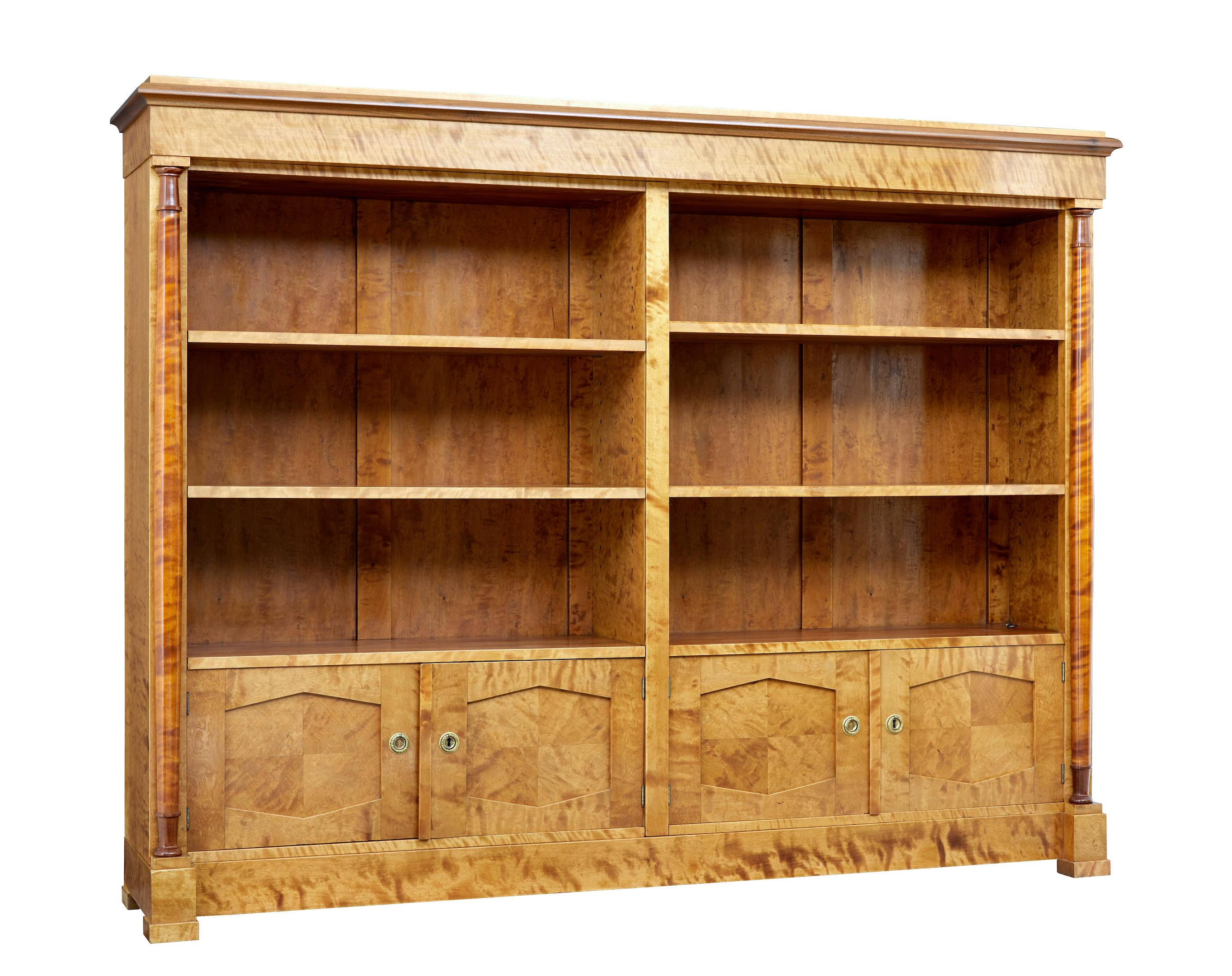 Impressive Art Deco period bookcase of large proportions, circa 1930.

Made with burr birch veneers. Shaped cornice stands above an open bookcase section with central partition. Each side with 2 adjustable shelves. Below are 2 double door