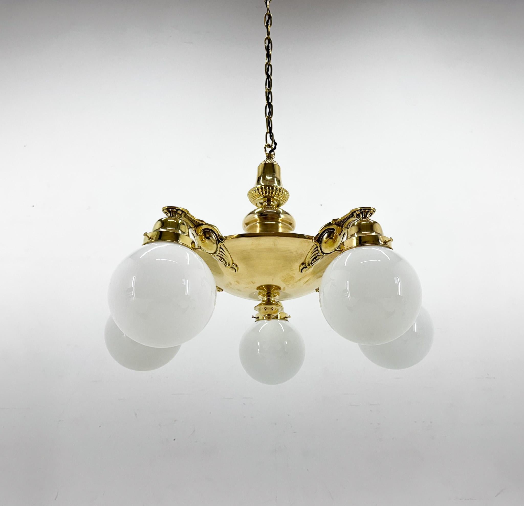 Großer Art-Deco-Kronleuchter aus der ehemaligen Tschechoslowakei. Hergestellt aus Messing mit fünf Milchglaskugeln. Glühbirnen: 5 x E 26 / E 27. US-Verkabelung kompatibel.