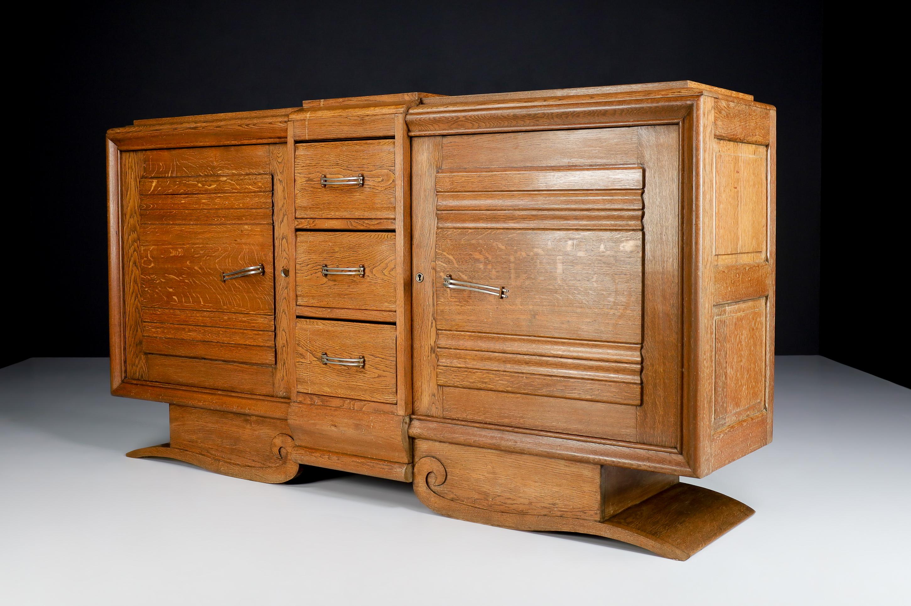 Large Art Deco Brutalist patinated oak Credenza , France 1930s

Large Art Deco Brutalist patinated oak sideboard by Gaston Poison France 1930s. This heavy Brutalist credenza seems to float on its elegant base. The credenza consists of two large