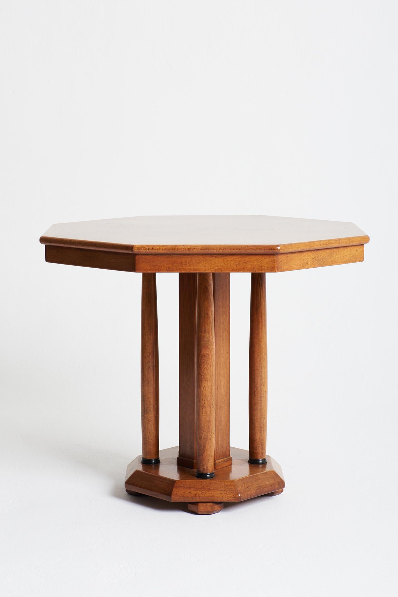 A large Art Deco octagonal mahogany centre table, the fine 'sunburst' veneered top supported by an octagonal pillar surrounded by tapered columns, on a bevelled octagonal base resting on faceted octagonal bun feet.
France, Circa 1930.