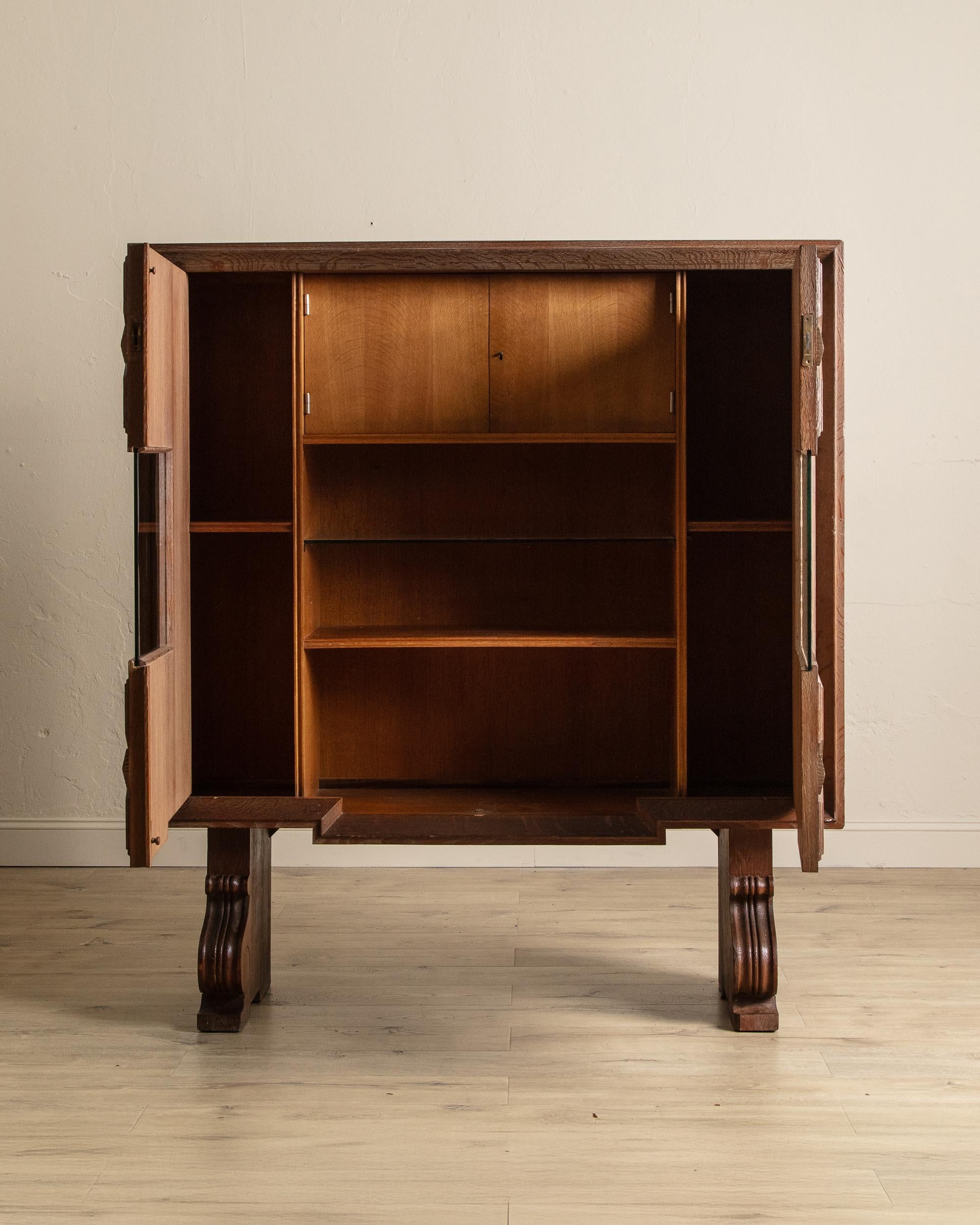 Ce meuble bar en chêne cérusé français, vers 1940, est un exemple raffiné de l'influence du début de l'Art déco, alliant fonctionnalité et design remarquable. Le meuble comporte deux portes à panneaux complexes qui s'ouvrent pour révéler une étagère
