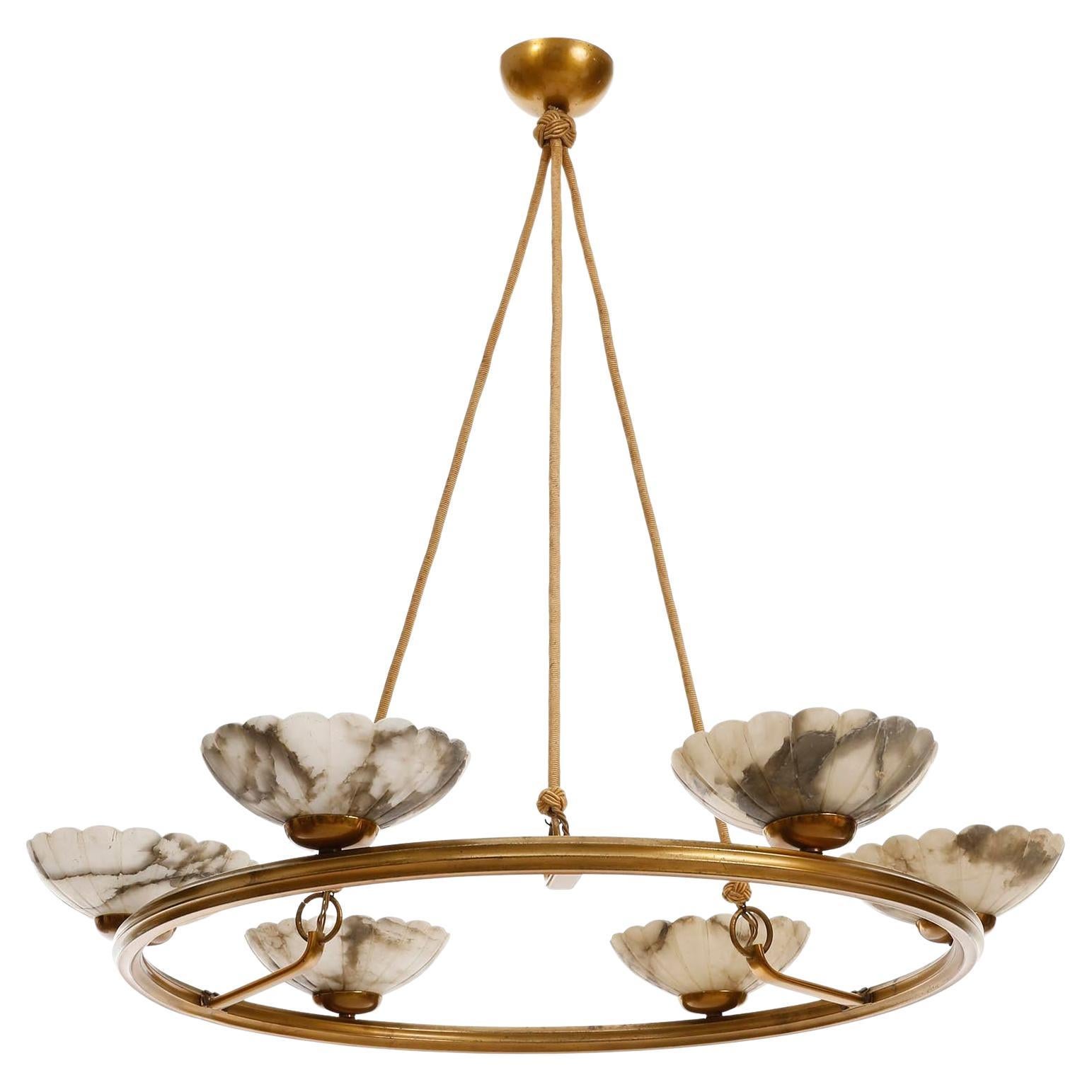 A large and gorgeous Art Deco pendant chandelier manufactured in Sweden, circa 1930.
It is made of a patinated brass or bronze ring with six engraved and polished Alabaster lamp shade bowls.
The alabaster bowls have a wonderful texture and