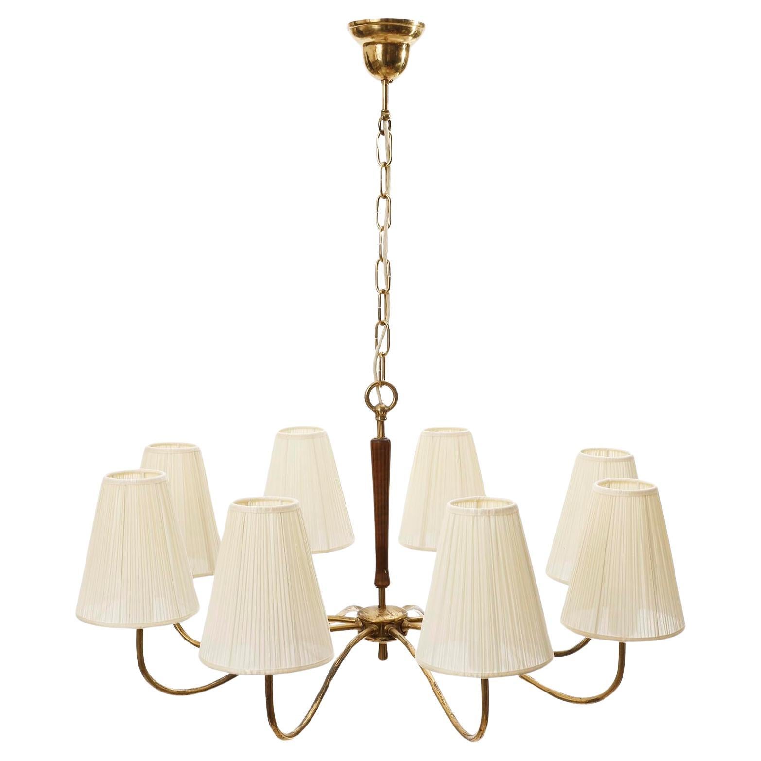 A fantastic eight-arm pendant chandelier made of stained wood and brass with organically curved arms and cream colored pleated fabric shades, manufactured in Austria in 1930s.
The brass parts have lovely patina and a warm aged hue. The lamp shades