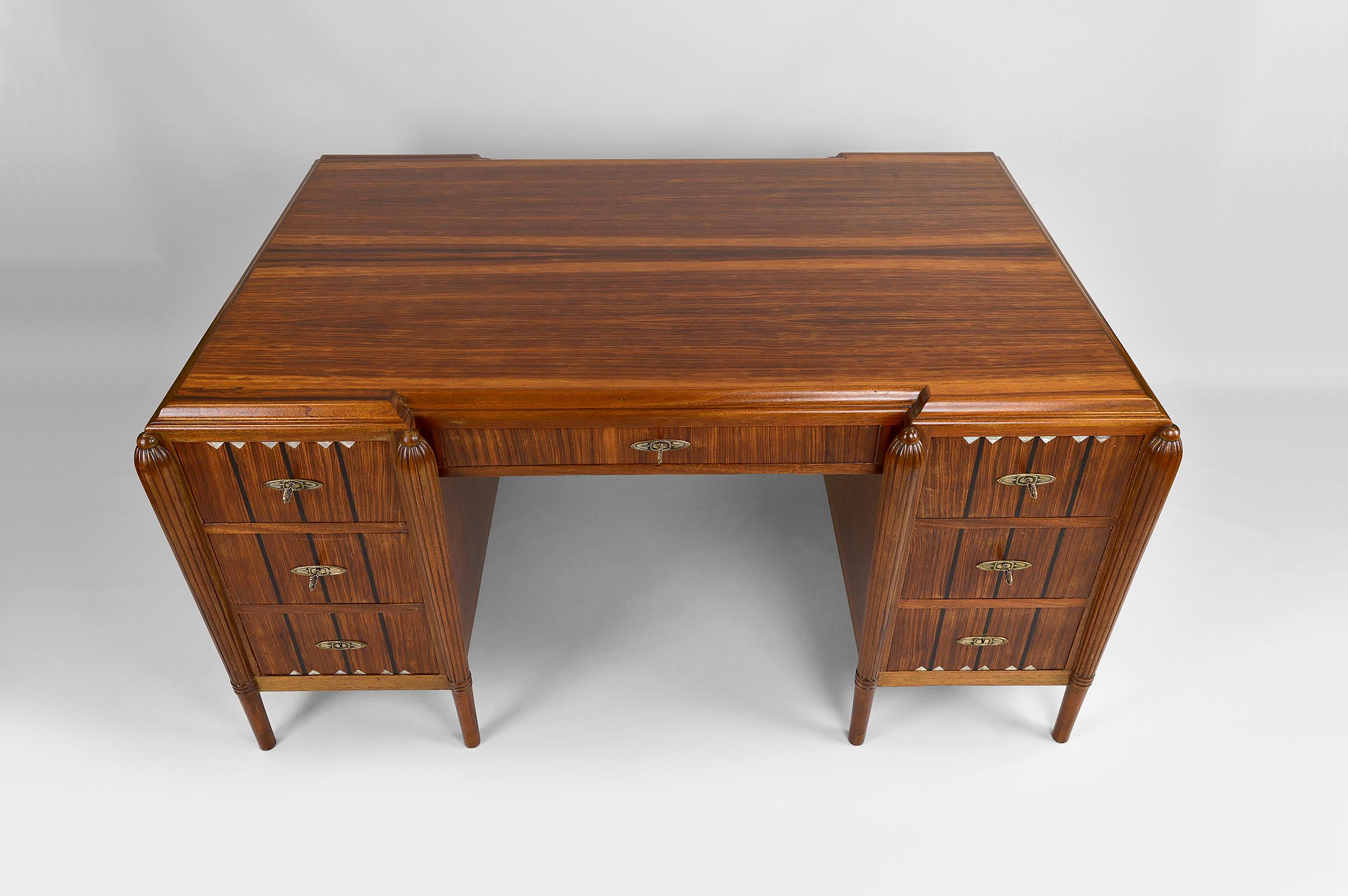 Large and important Art Deco pedestal desk.

Rosewood structure with elegant mother-of-pearl and ebony inlays.
Tapered and fluted legs.
Nickel-plated / silvered bronze keyholes and keys.

1 central drawer and 6 side drawers.
6 keys present.
