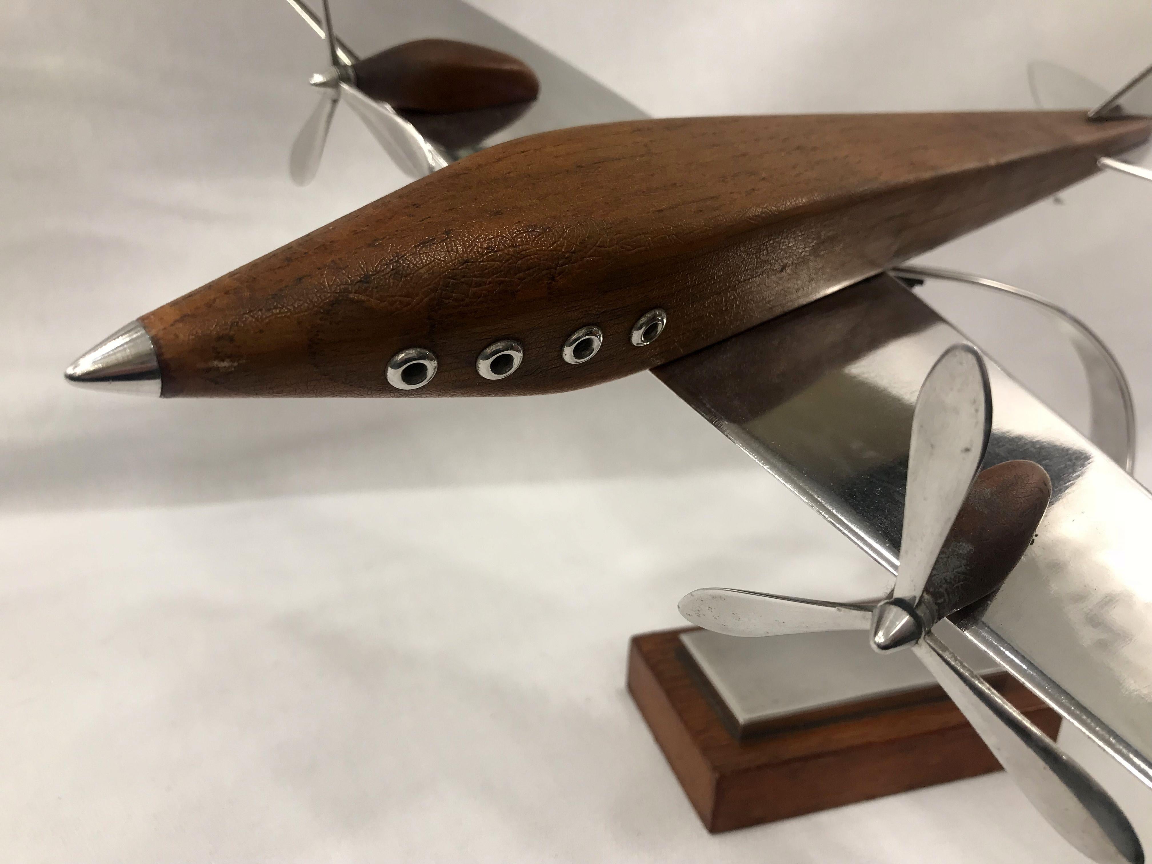 This is a large 1930s desk model of a stylised Art Deco airplane made from teak wood and aluminium steel on an arching steel stand and teak base.
   