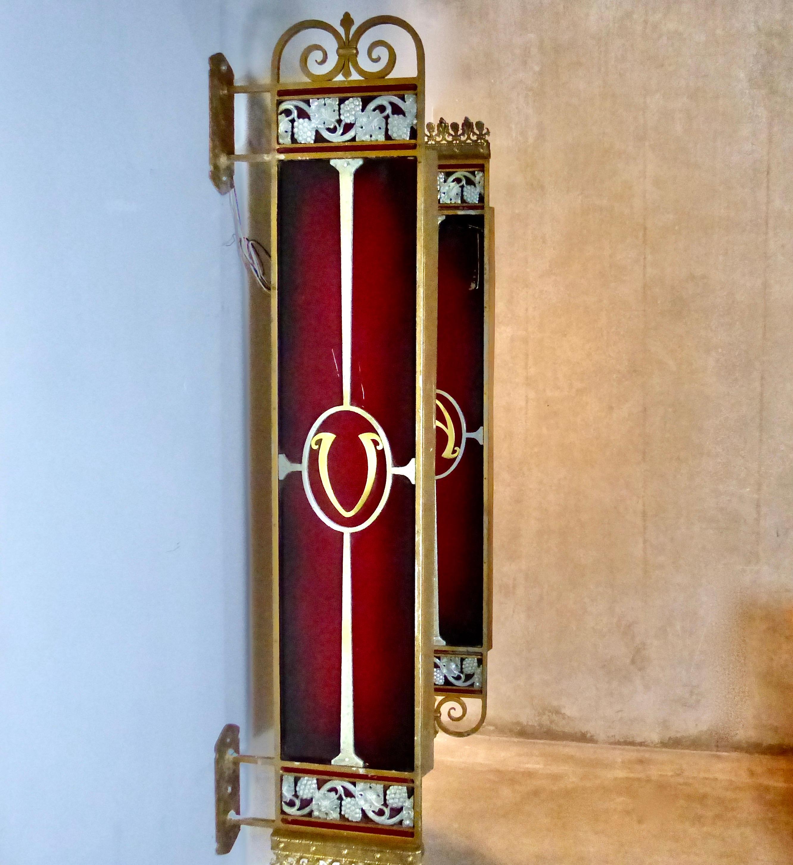 A matched pair of elegant Art Deco era movie theatre lights finished in red enamel with some gilt. Brass light housing, along with cast metal ornamentation, complete the spectacular design. Re-wired and CSA approved to current electrical standards.