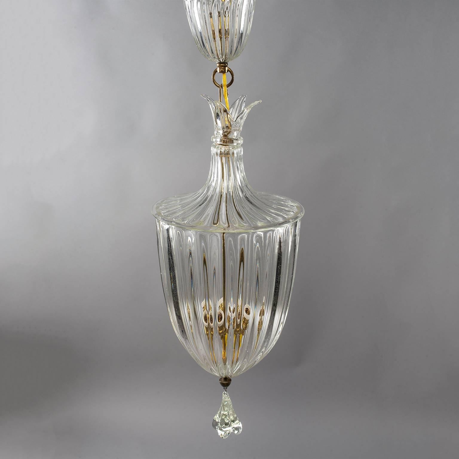 Murano glass lantern style pendant attributed to Barovier and Toso, circa 1930s. Thick clear handblown glass with polished brass hardware. Main vessel has three internal candelabra sized sockets, large clear glass dangling pendant, glass topper,