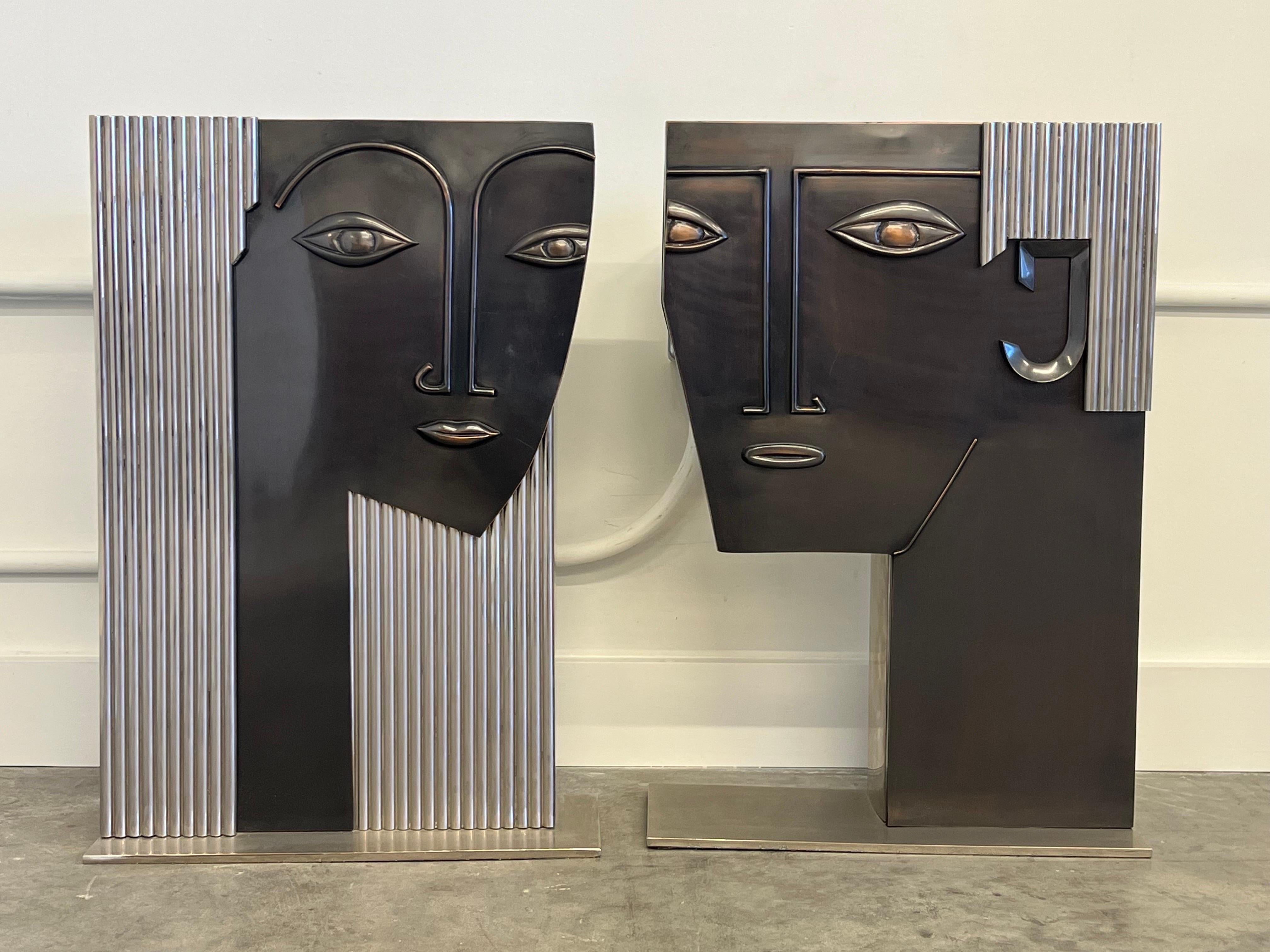 A pair of statement sculptures that can dual as a flower vase, umbrella stand, or just purely aesthetic. Extremely well made metal fabrication made in the manner of Franz Hagenauer. Asymmetrical stylized faces with chrome steel box as support. The