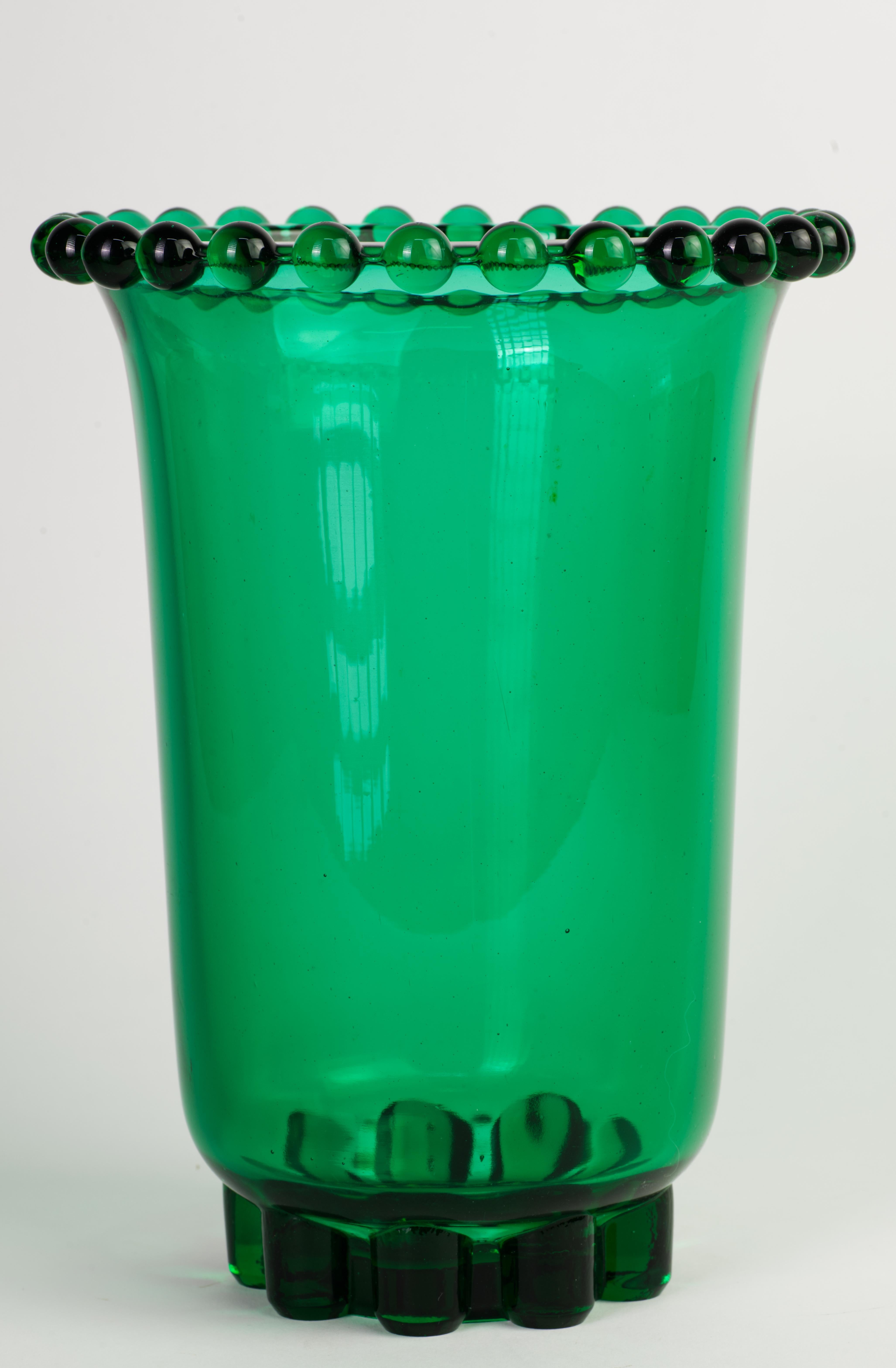  Il grande vaso in stile Art Deco è stato realizzato in vetro verde con tonalità gioiello, con bordo e base scultorei e dettagliati e corpo cilindrico di forma minimale. Il vetro contiene uranio e il vaso si illumina alla luce UV; vedi le immagini.
