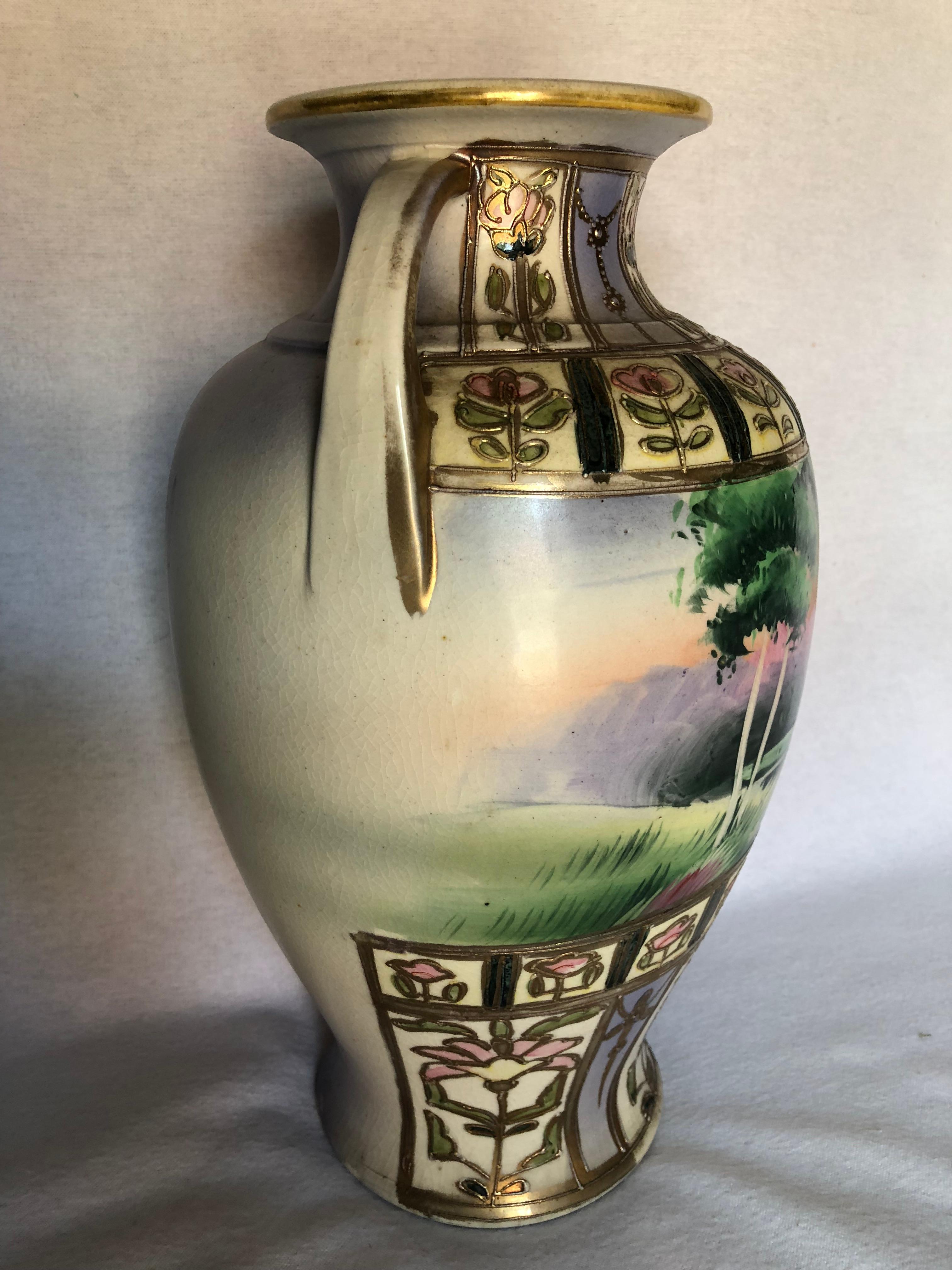 This Art Deco two handled vase features a hand-painted lake scene. The top and bottom features raised intricate Deco stylized floral designs. Its coloring makes it a very versatile decorator piece. The finish has some light crazing and gold loss