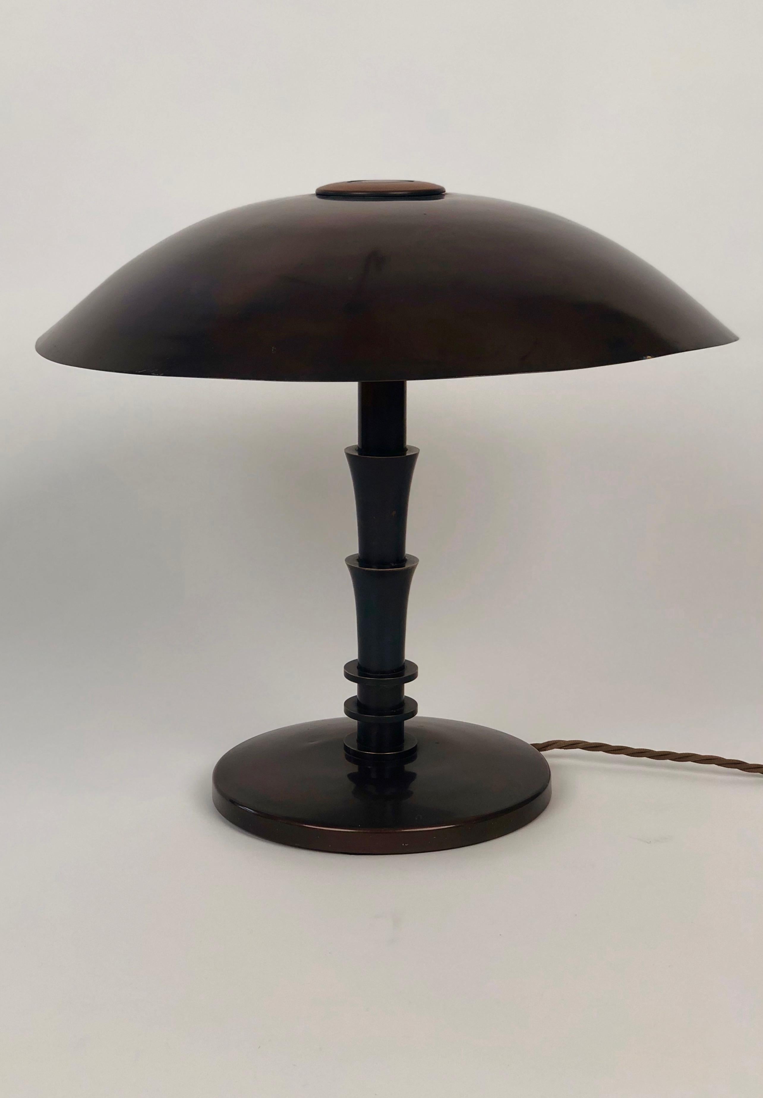 A hand made Art Deco table lamp in a geometric style from brass , 1930's , Vienna.

The form of the  base has rounded edges that contrast to the geometric, step like stem
the overall effect with the bronze patia is one of elegance.

Special to this