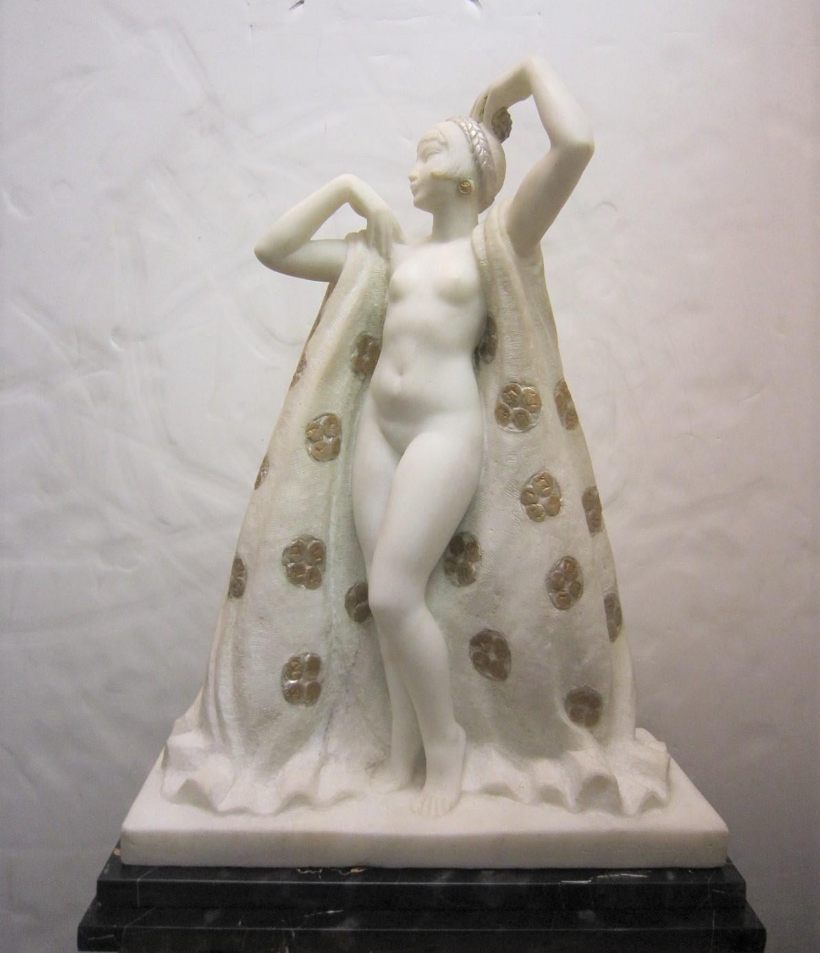 An elegant French, original hand carved natural specimen Carrara marble sculpture of a standing nude woman delicately balancing her hands above her head while royally wrapped with a cape. The figure is mysteriously concealed from behind, yet