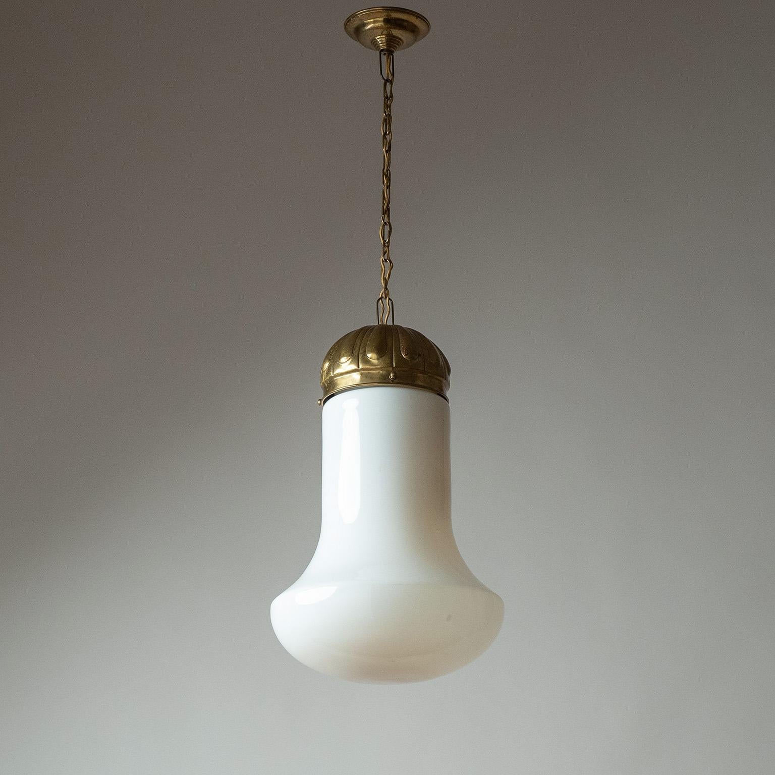 Art Deco milk glass pendant from the 1920-1930s. Nicely detailed brass hardware with a large bell-shaped blown glass diffuser, which has some varying degrees of opacity. One original brass and ceramic E27 socket with new wiring. 
Measures: Height