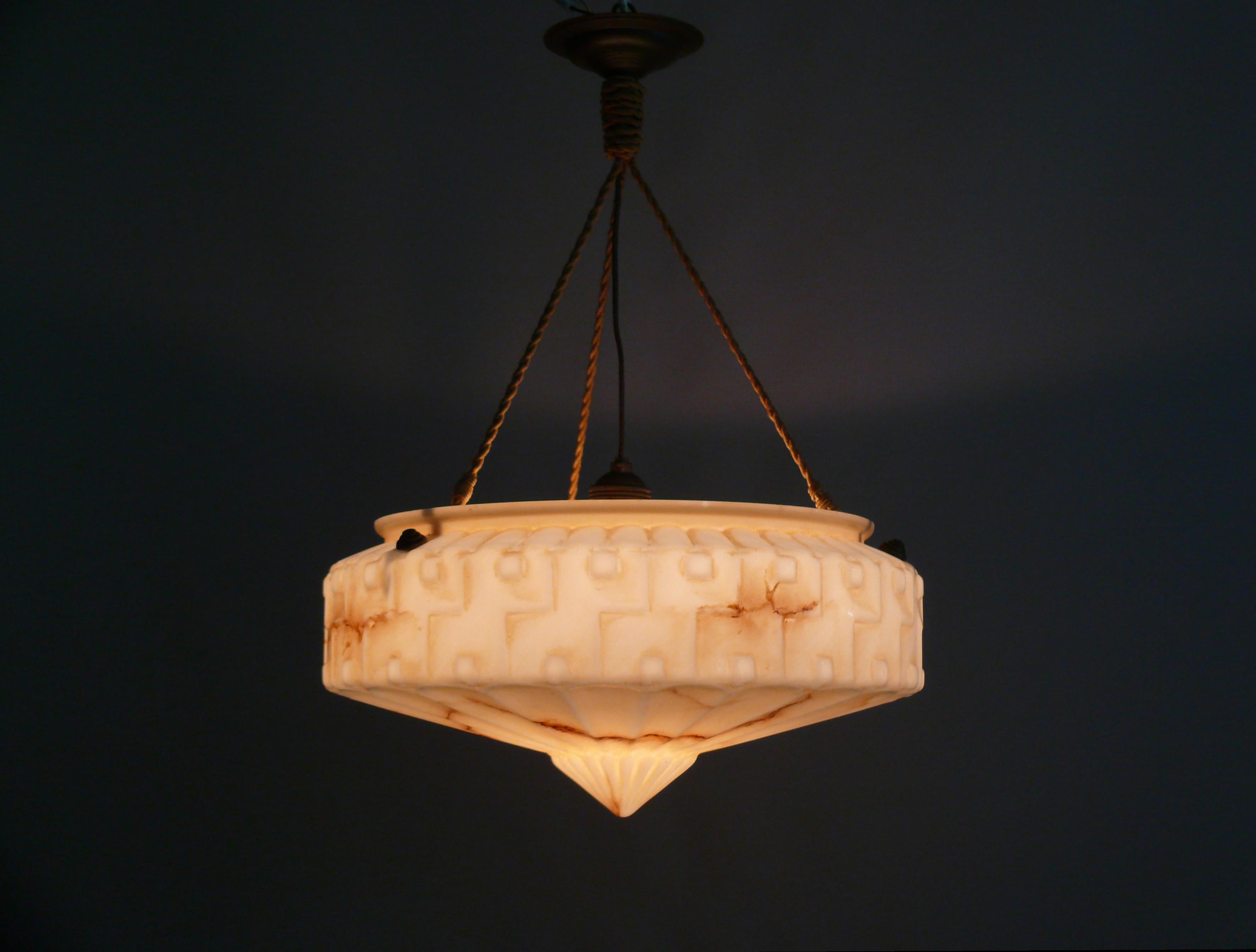 Rare Art Deco pendant lamp from the 1920s-1930s with a marbled glass shade and cable suspension in good original condition.

The large white glass shade has a beautiful shell-like shape with brown marbling, a surrounding geometric frieze, and a