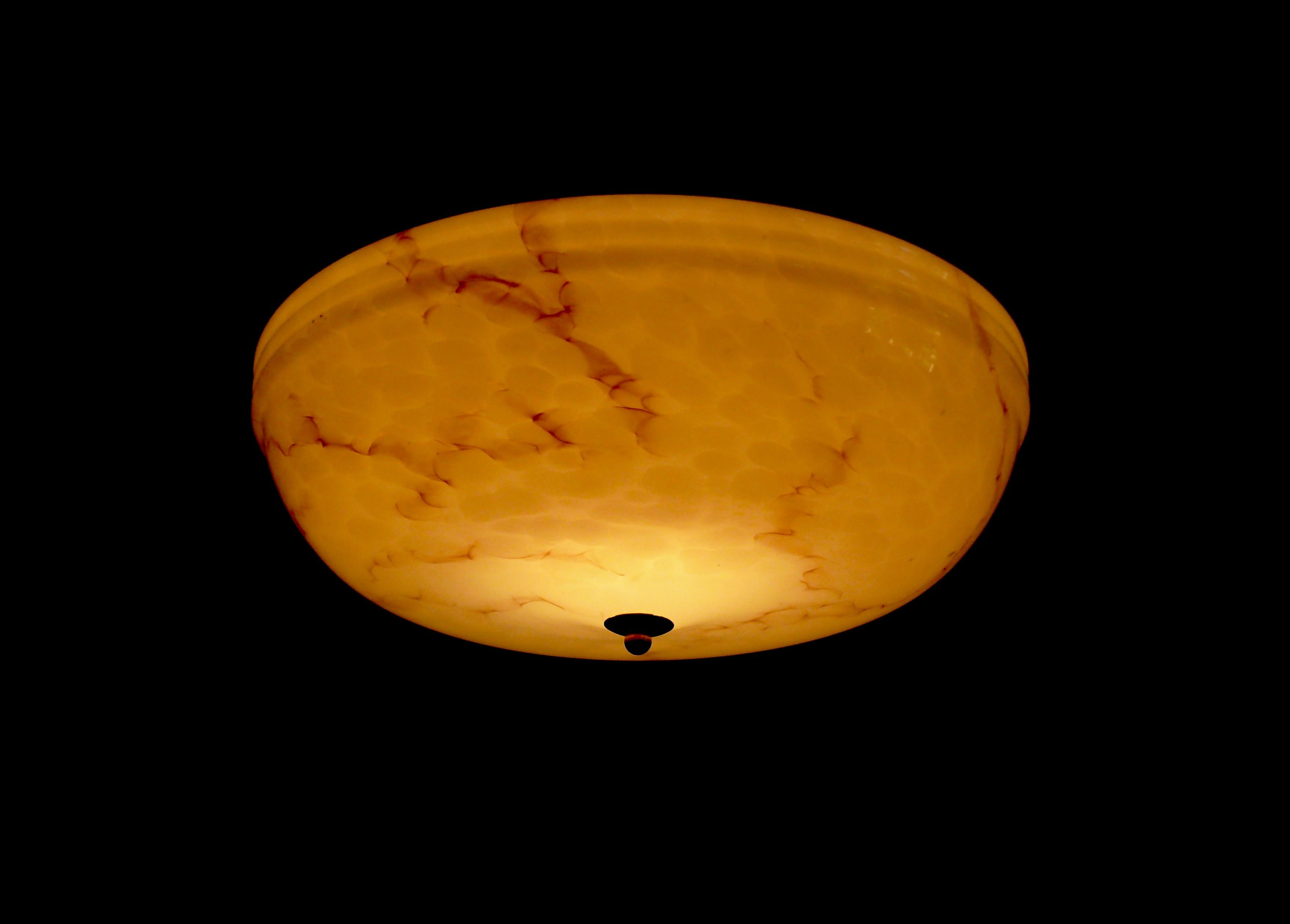 Lampada a sospensione a stelo Art Deco degli anni '30-'40 con un paralume in vetro beige splendidamente profilato. Il paralume in vetro è marmorizzato e in ottime condizioni. La sospensione è in ottone e l'asta è stata sostituita da uno stock