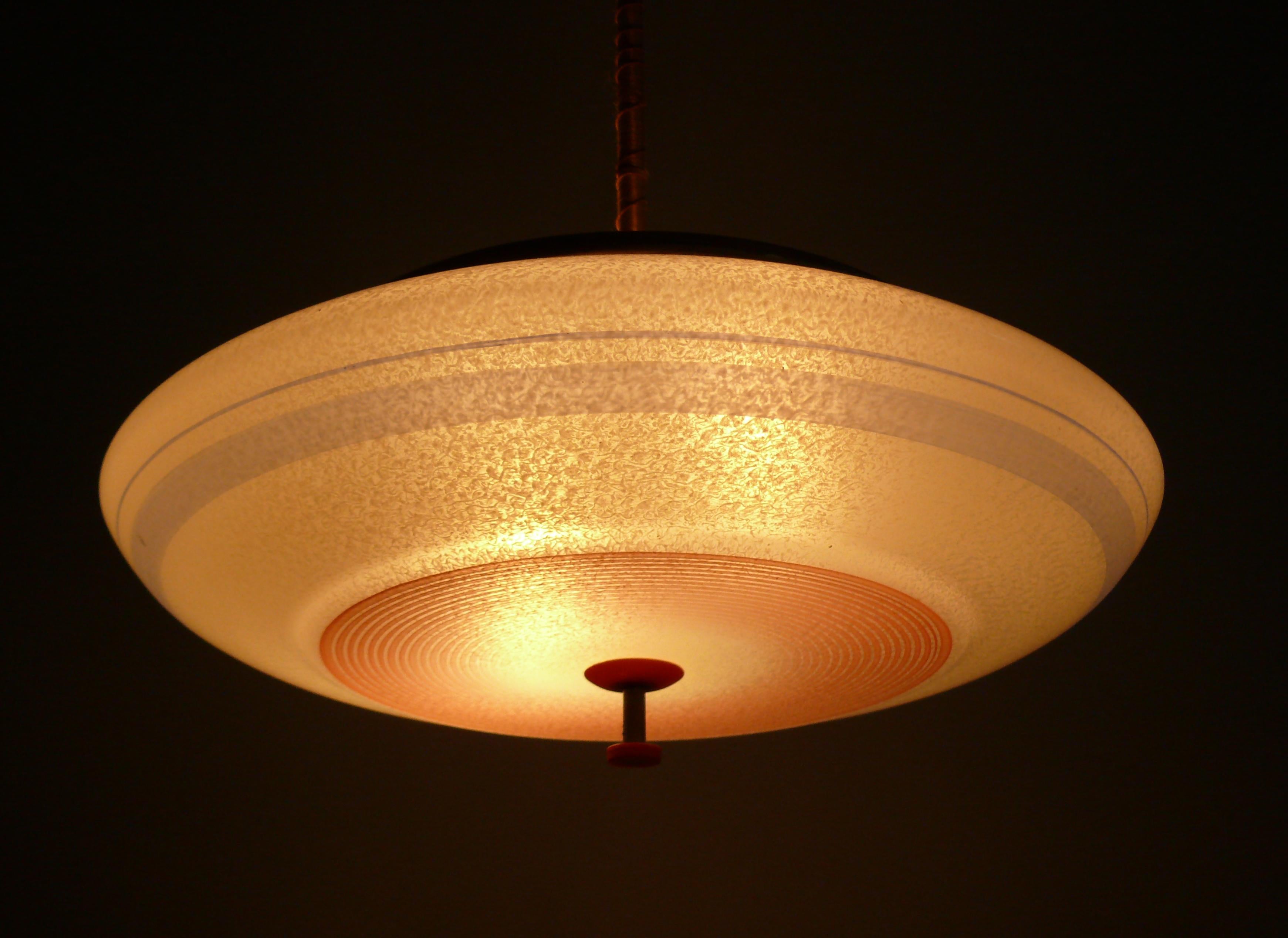 Large Art Deco rod pendant lamp with a decorated, UFO-shaped glass shade from the 1930s. The glass shade is in very good condition, as are the radial stripes. The glass holder was rebuilt from wood and the glass holder was replaced. The canopy is