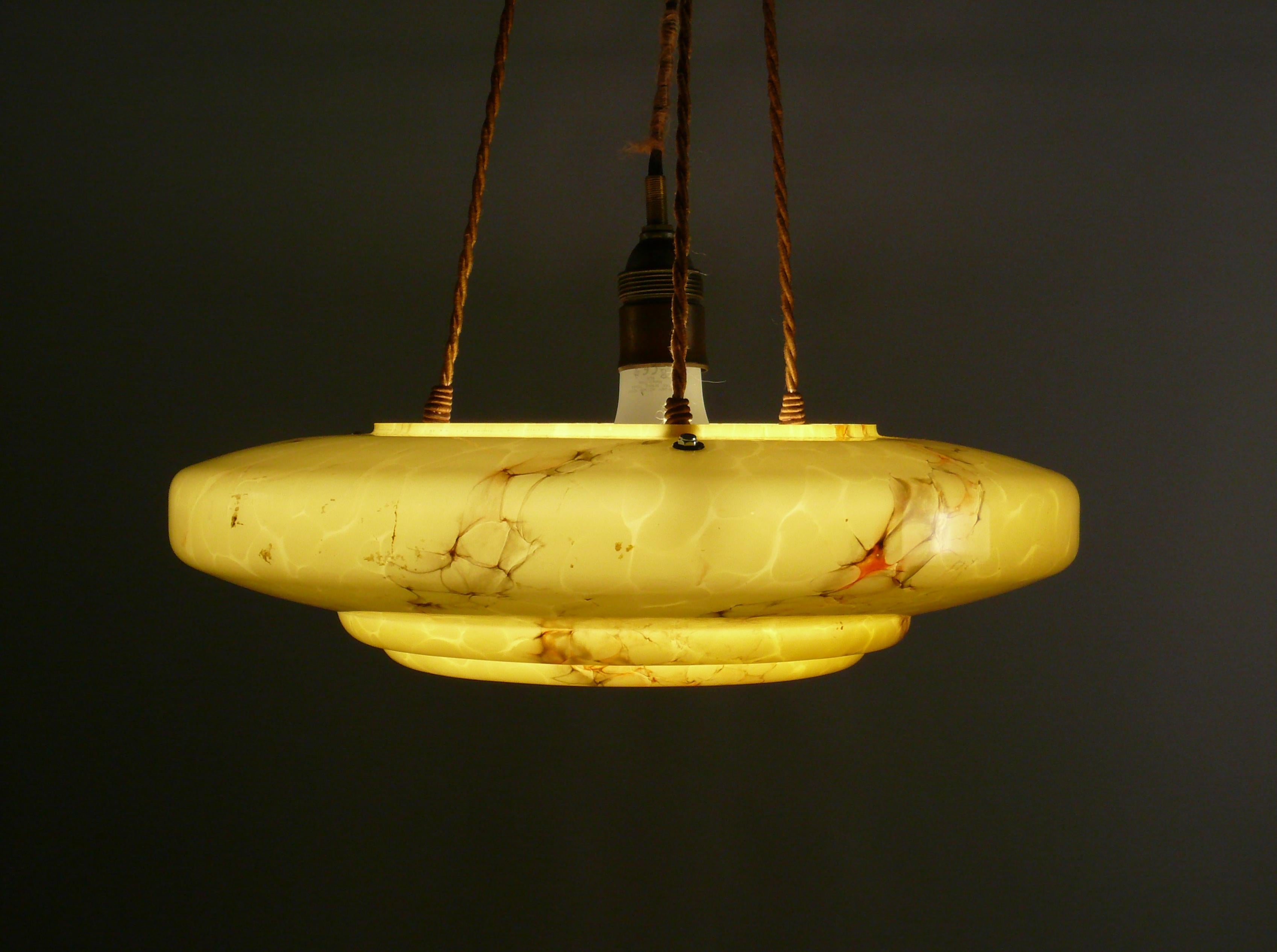 Grande et très belle lampe suspendue des années 1920-1940 avec un abat-jour en verre marbré dans le design typique de l'Art Déco et en très bon état. L'abat-jour en verre jaune foncé a une très belle forme et de subtiles marbrures. Le verre est
