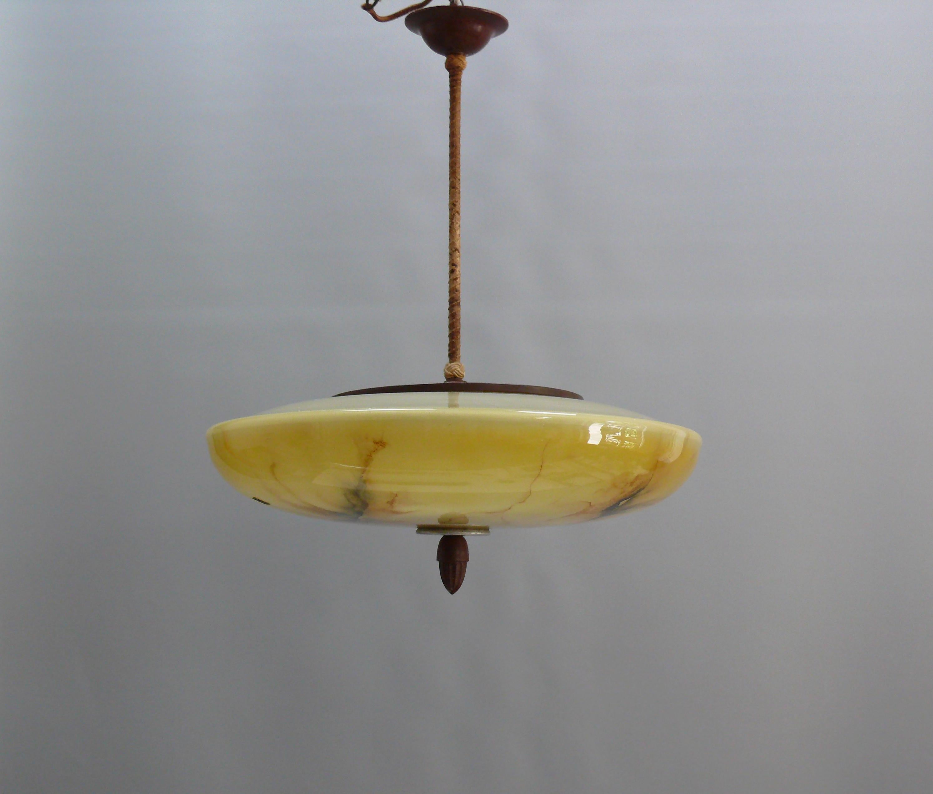 Large rod pendant light from the 1930s-1950s with a yellow glass shade and wrapped pendulum rod.

The UFO-shaped glass shade features a beautiful marbled pattern and a decorative Bakelite knob on a metal plate at the bottom center. The glass holder