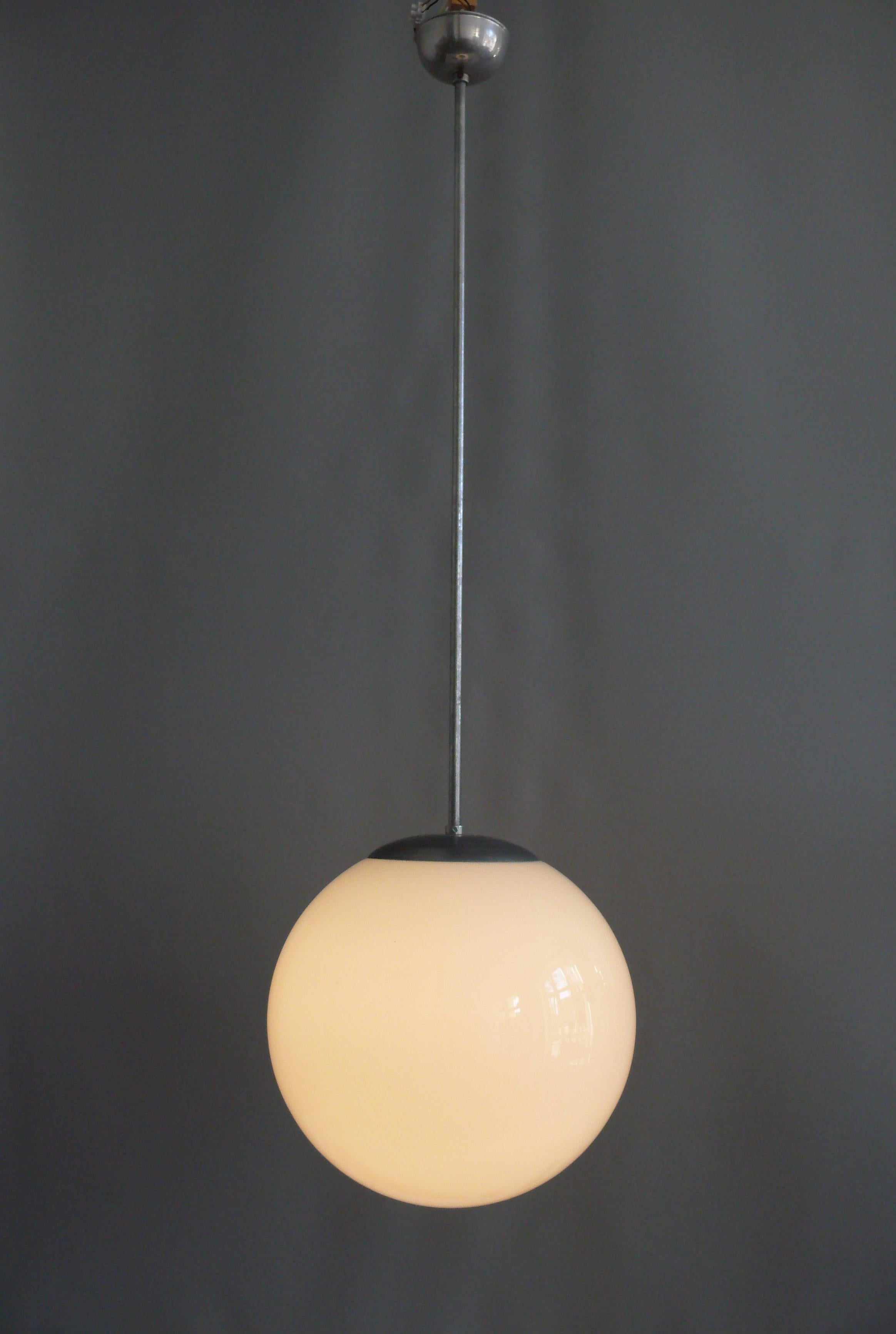 Large Bauhaus spherical lamp made of opal glass with a metal suspension and a very long pendulum rod. The lamp dates from the first half of the 20th century (1920-1940) and is in good, working condition*. The surfaces of the metal parts (probably