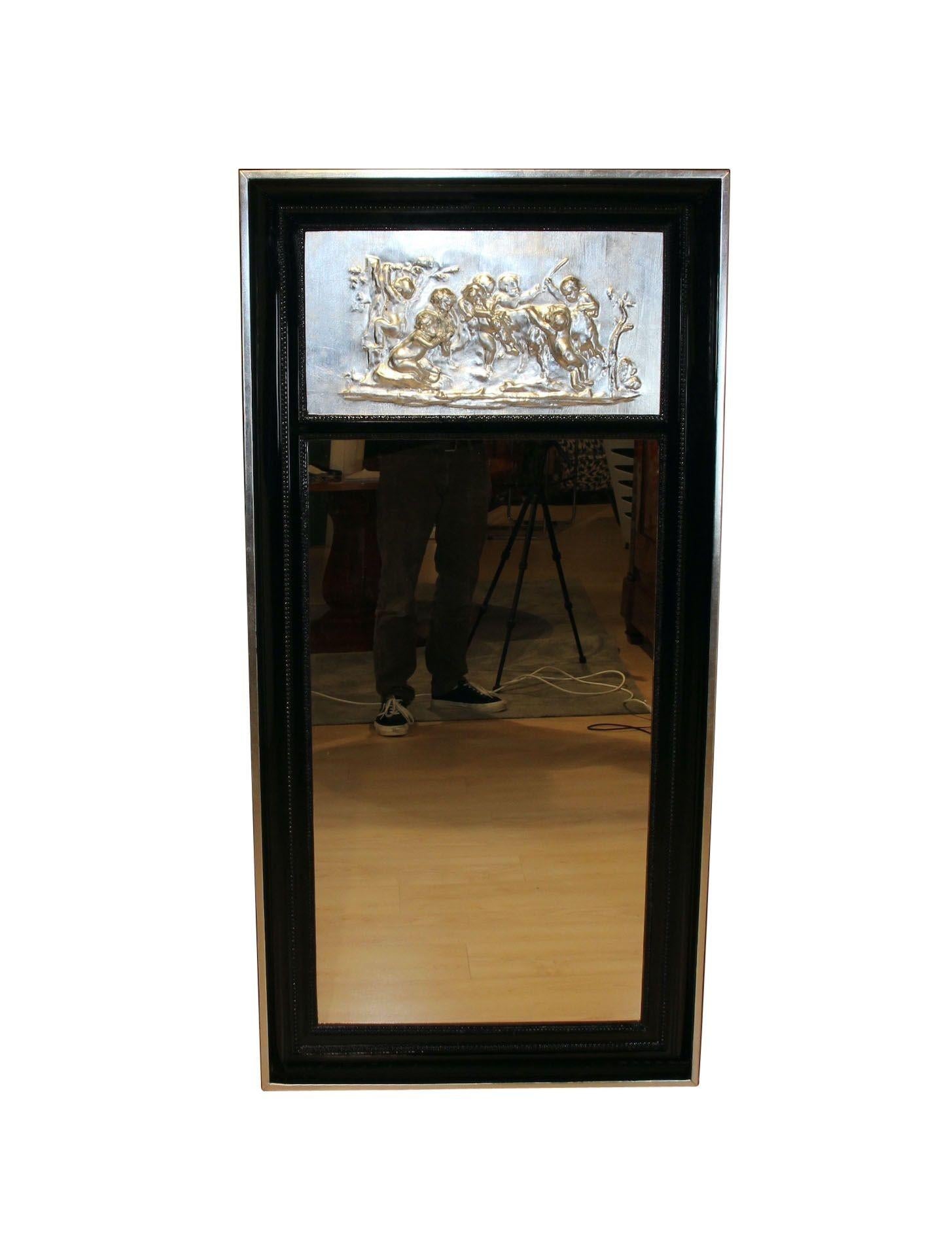 Large Art Deco Pillar Mirror, Black Lacquer and Silver-Leaf, France circa 1920.
Black piano lacquer wood. Hollow frame with two beaded strips.
Above, silver-leaf plated plaster decoration of a putti scene. Outer rim with silver leaf plate