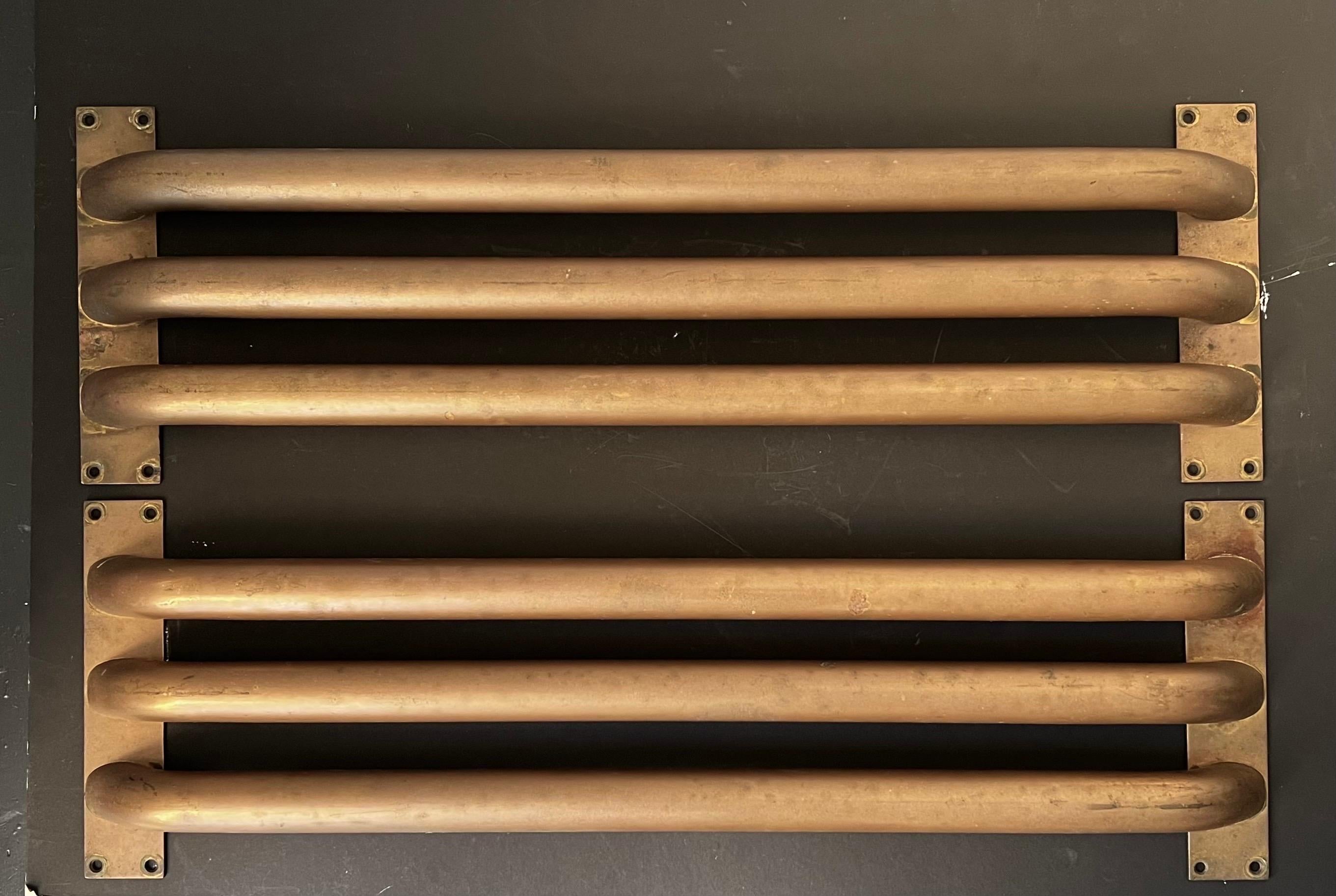 A set of two large lateral push-pull door handles of tubular brass. English, art deco style, 20th century. 

A striking set - each piece made to span the full width of a door - the handles are formed from three brass sections, curved at the ends,