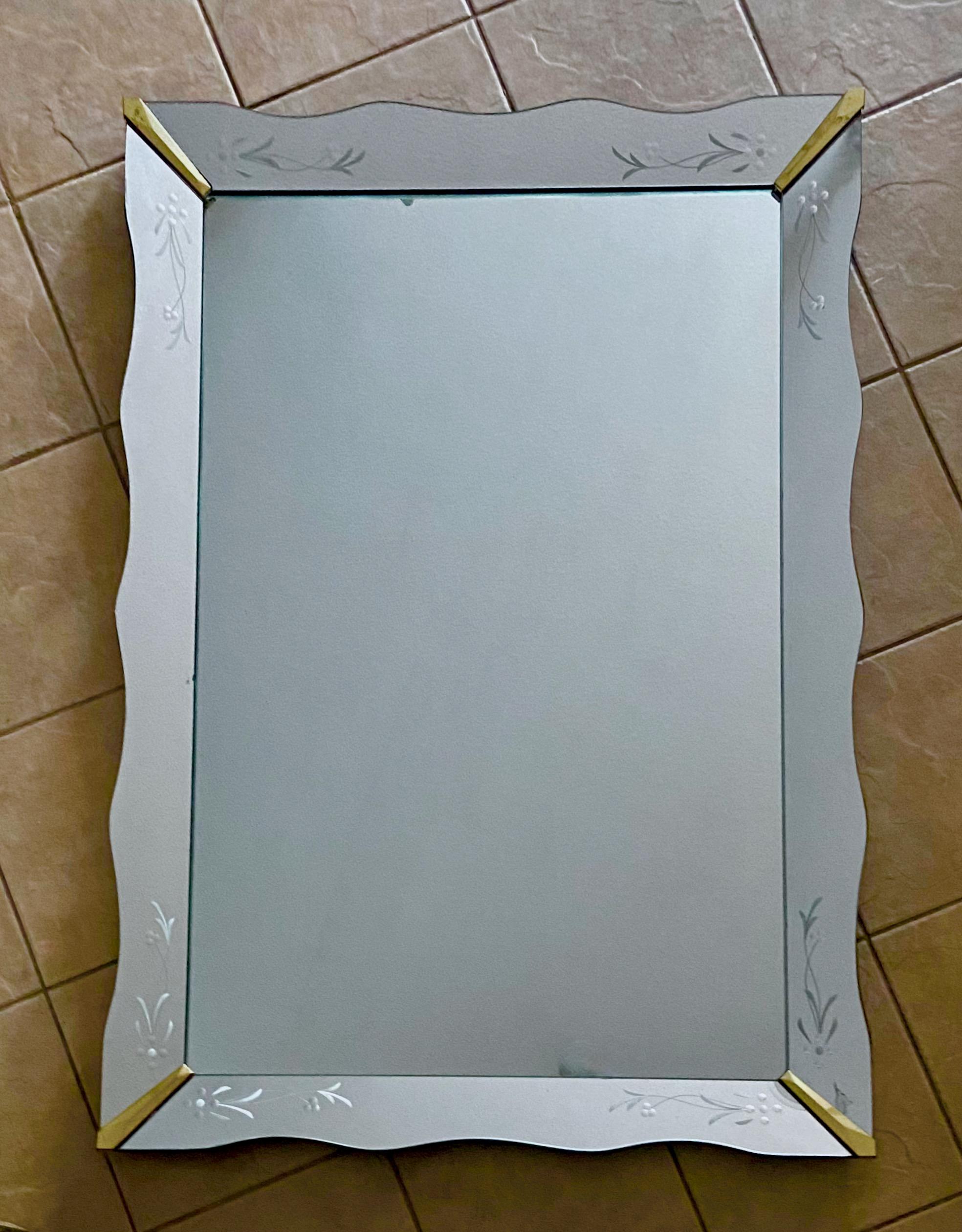 Large rectangular Art Deco Venetian style scalloped or wavy edge wall mirror with brass corners and etched mirrored panels.

Measures: 54