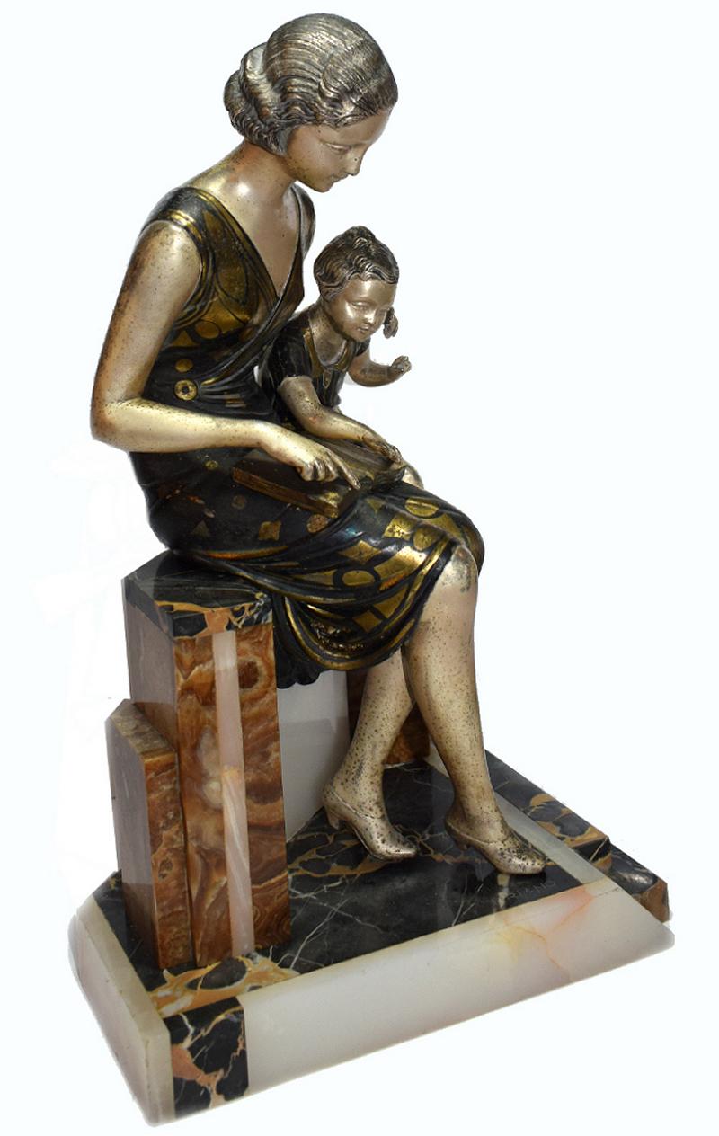 A beautiful and totally original Art Deco sculpture from the first half of the last century. Depicting a figure of a woman who is reading to her young son from a book. The sculpture is signed on the base URIANO. Made from spelter and cold painted