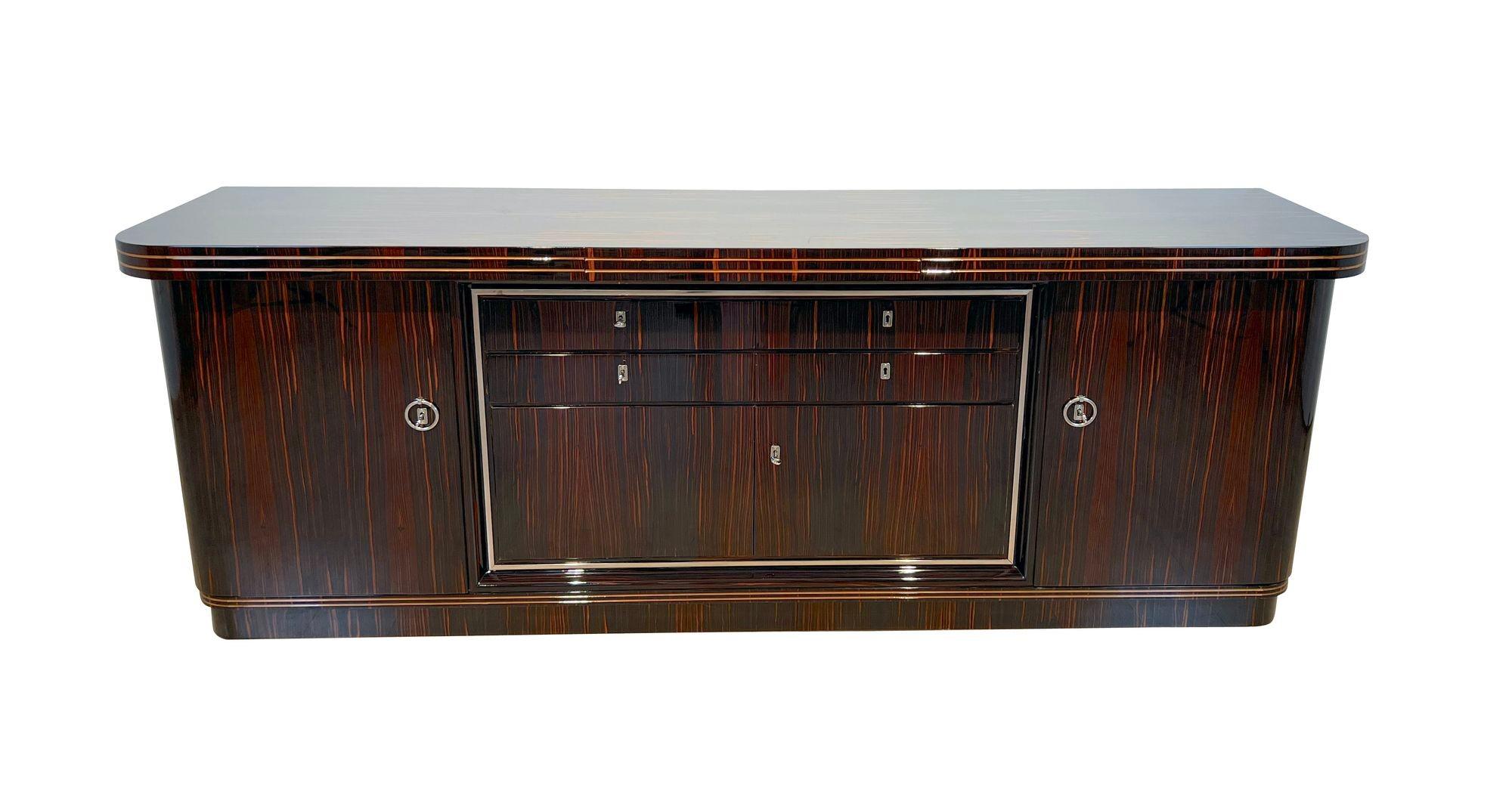 Large original Art Deco Sideboard in Macassar Veneer from France about 1930.
Macassar Veneer, high-gloss lacquered and polished. Maple inlay decorative bands. Original, chrome-plated metal fittings.
Two large doors on the sides and four drawers and
