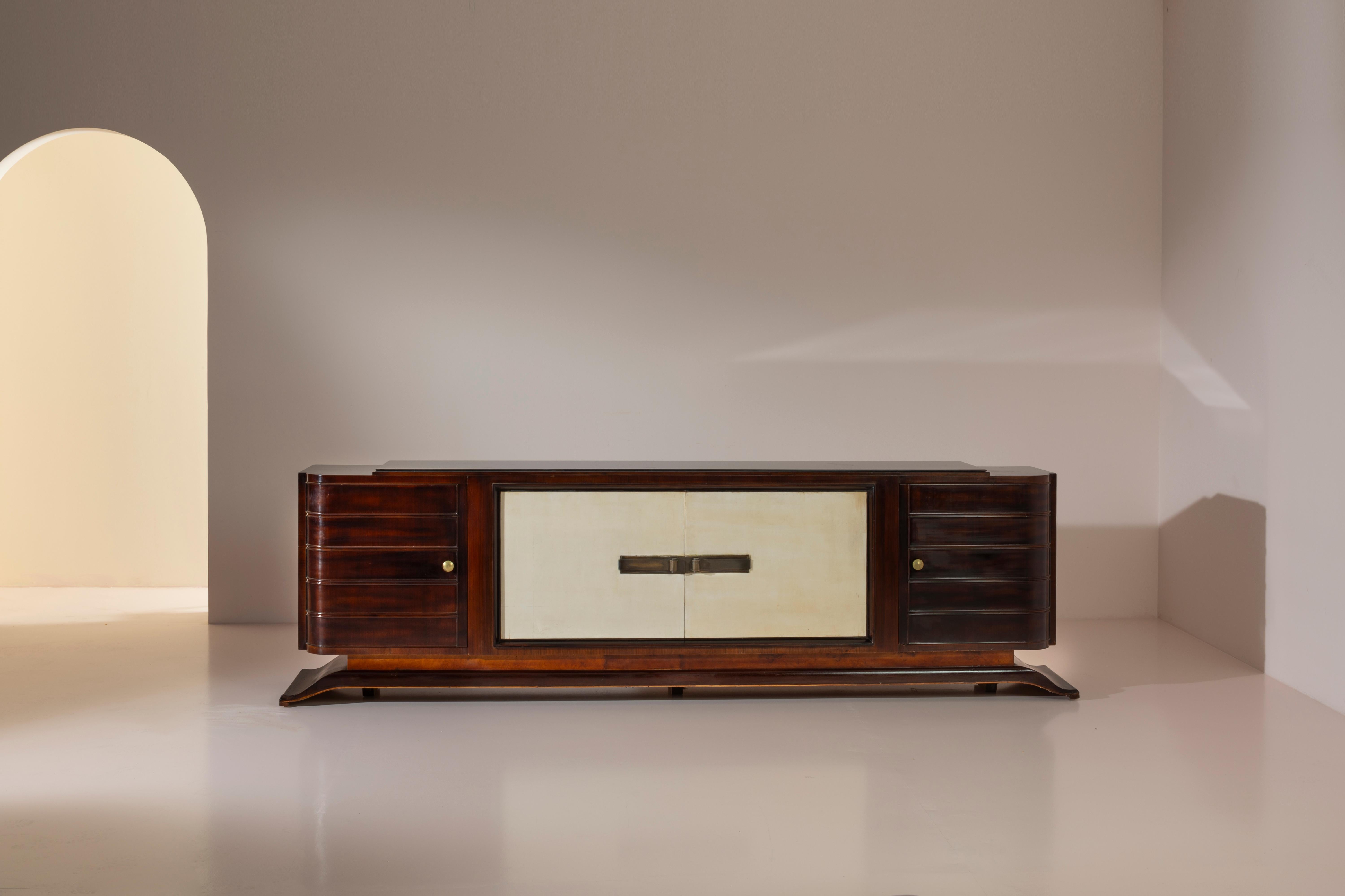 Gran aparador de madera de nogal americano con incrustaciones de pergamino y tapa de cristal negro, de la época Art Déco, fabricado en Italia.
Una gran pieza de comedor diseñada para interiores espaciosos de principios del siglo XX. Encarnando la
