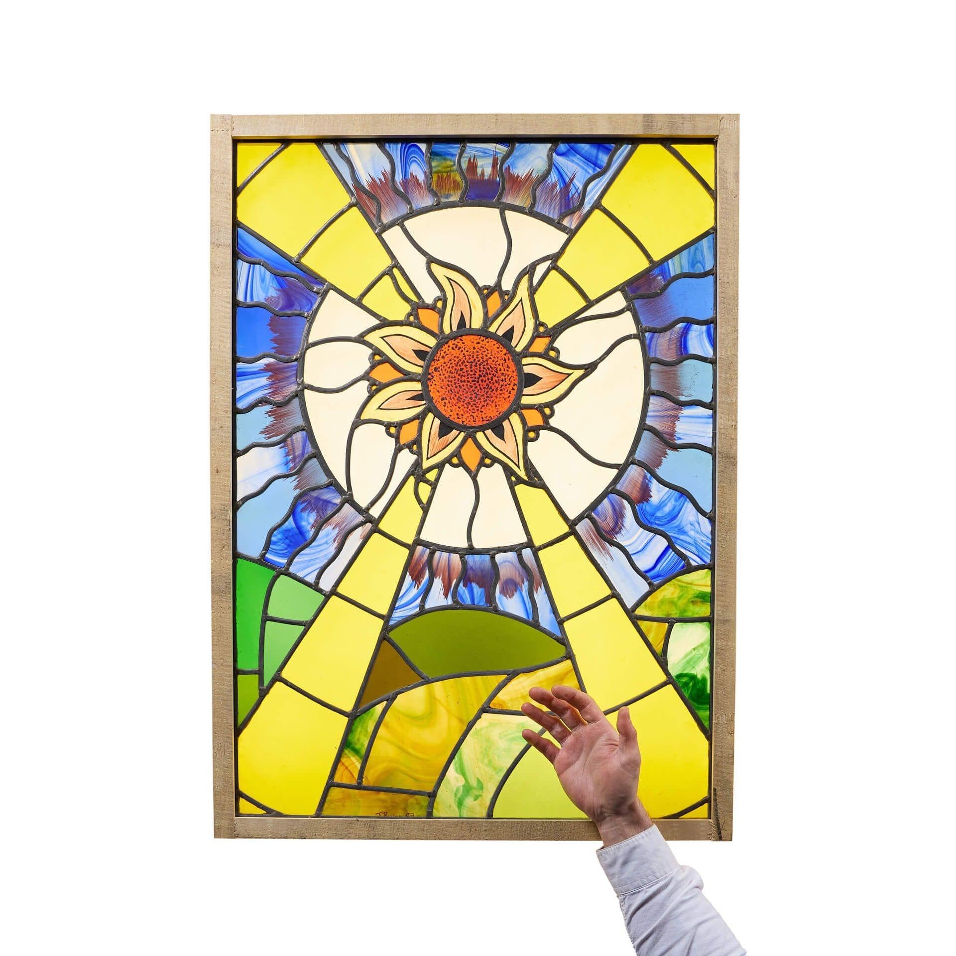 Un grande pannello in vetro colorato piombato in stile Art Déco, che raffigura il sorgere del sole su un paesaggio montuoso e un cielo blu intenso.

Si tratta di una vetrata astratta contemporanea dal design insolito, che unisce una serie di colori