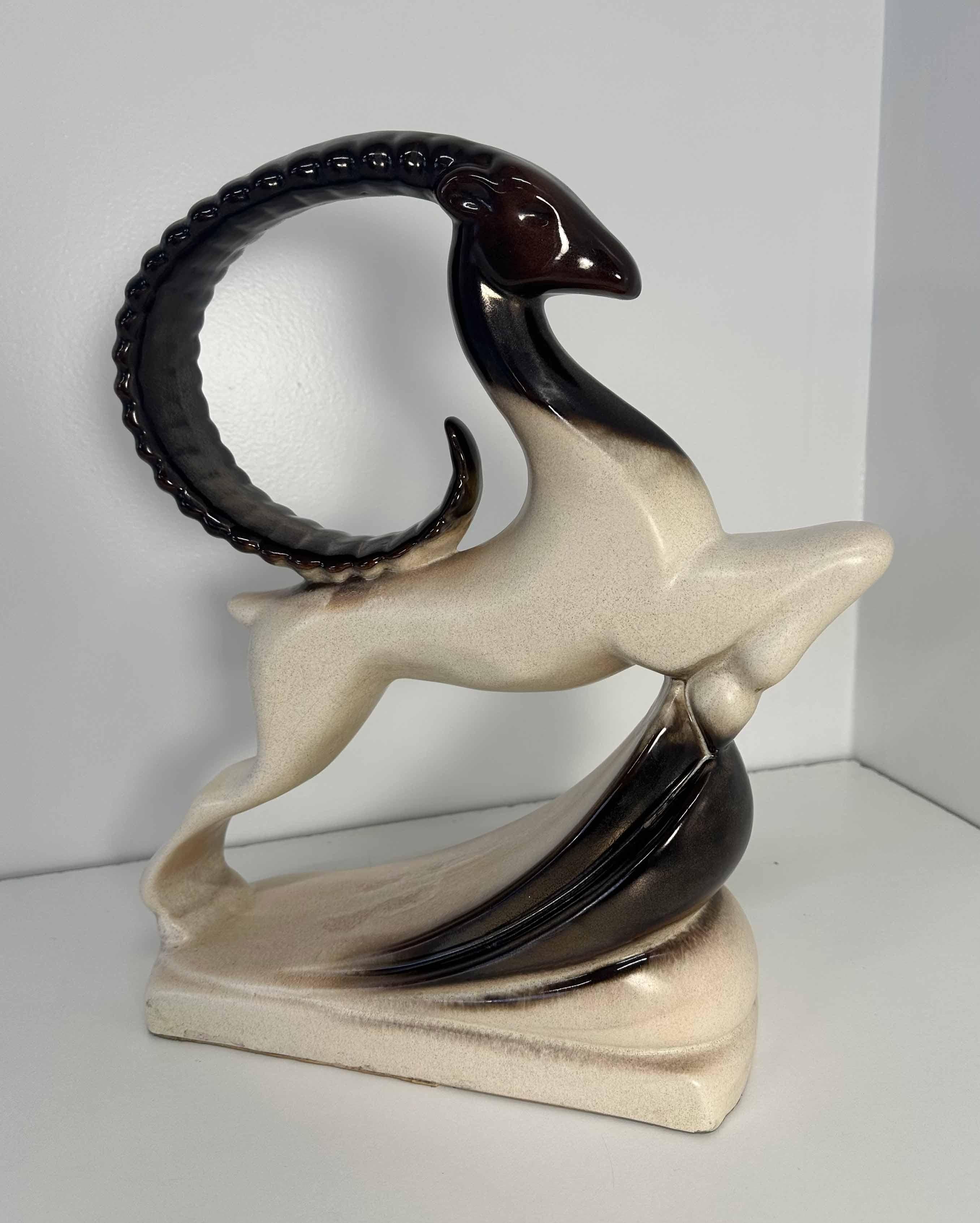 This large Art Deco style ceramic was produced in the USA in the 1960s by Royal Haeger. 
It features a bicolored, deep brown and white leaping ram with a high gloss glaze finish. 
It is in very good vintage conditions.