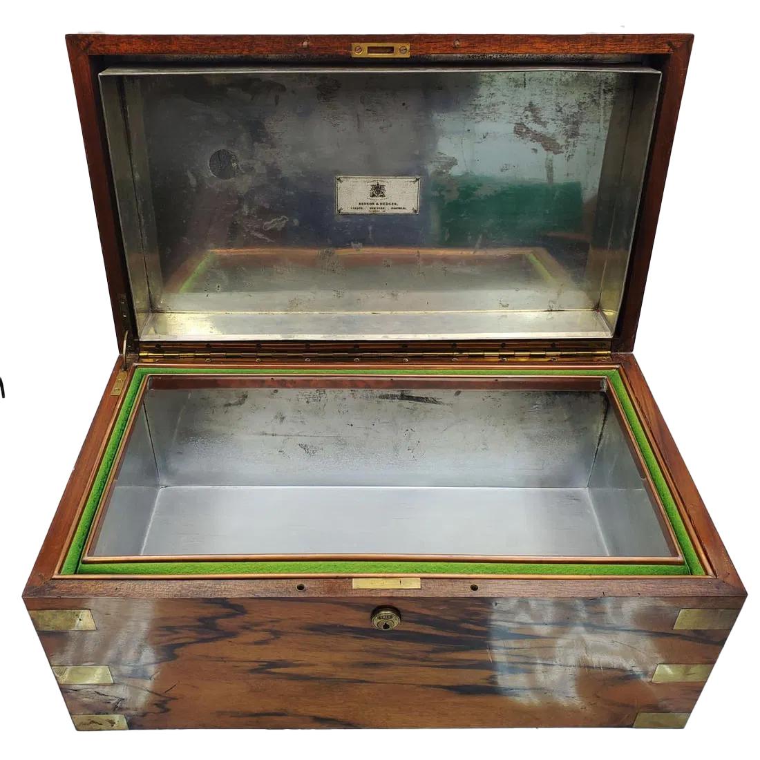 Großer, abschließbarer (inklusive Schlüssel) Humidor im Campaigner-Stil aus stark gemasertem Holz mit eingelegten Messing-Eckstützen und bündig montierten Griffen. Der Innenraum ist mit einer verzinkten, dicht schließenden Metallauskleidung