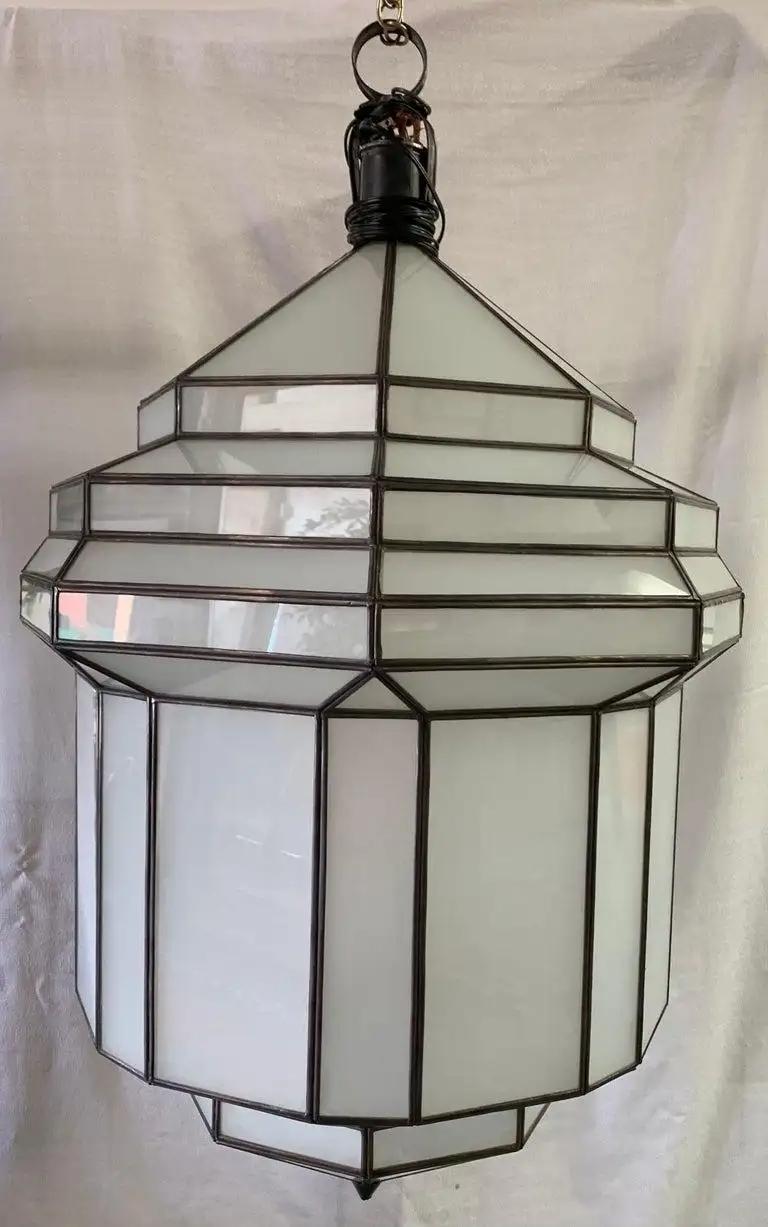 A gorgeous large Art Deco white milk glass handmade chandelier, pendant, or lantern. Handcrafted and having individual panes, the large Art Deco hanging lantern or ceiling fixture features sandblasted frosted milky glass and patinated metal frames.