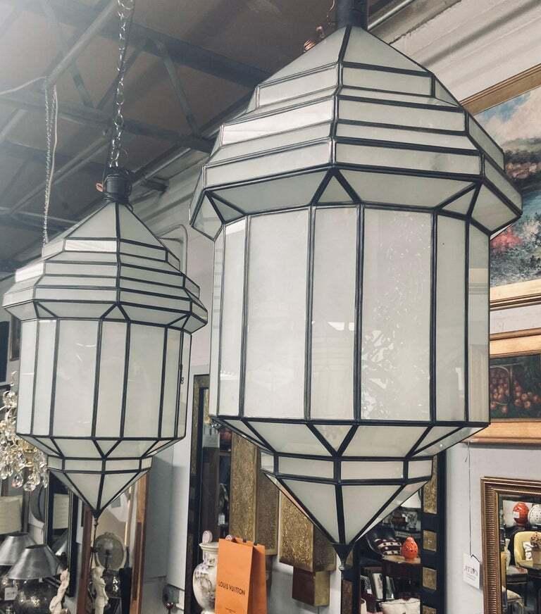 Large Art Deco white milk glass handmade chandelier, pendant, lantern, a pair
A gorgeous handcrafted, having individual panes, pair of large Art Deco hanging lanterns or ceiling fixtures featuring sandblasted frosted milky glass and patinated metal