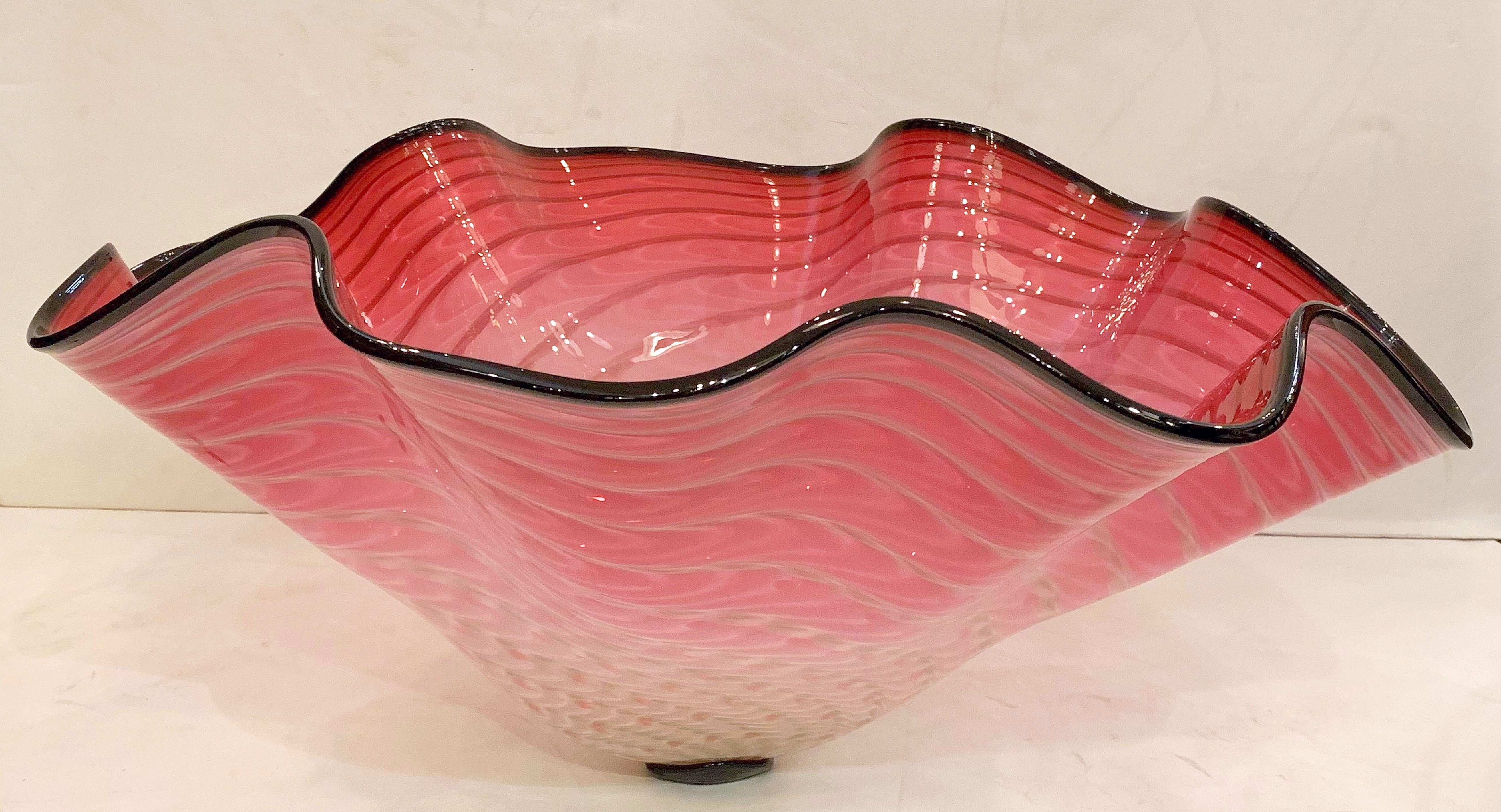 A beautiful large art glass bowl featuring a fused black glass rim with a ruffled edge, in the style or manner of Dale Chihuly.

Signed on base.

Dimensions of diameter vary from 22 to 26 inches.
