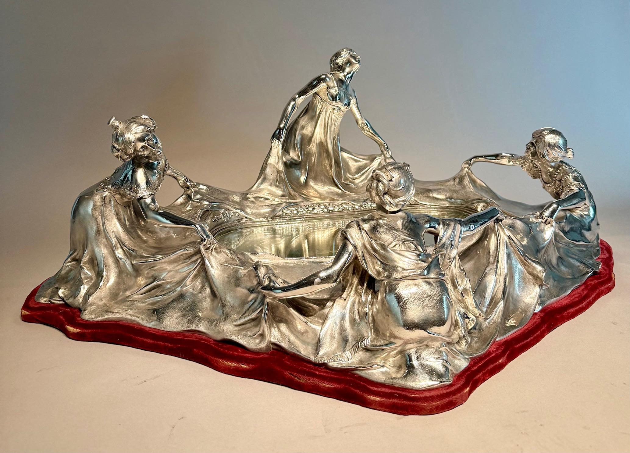 Large Art Nouveau bronze Silver-Plated Centerpiece. Circa 1900s.

A magnificent and rare example of early 20th-century Art Nouveau design, this large silver-plated centerpiece features four elegantly draped female figures gracefully holding flowing