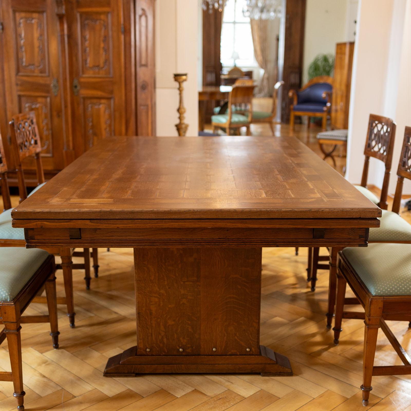 Large Art Nouveau extending table made of oak with a rectangular table top and two pull-out surfaces on the narrow sides. The table tops show a beautiful parquetry pattern. The maximum length is 360 cm. The table rests on two side panels with brass