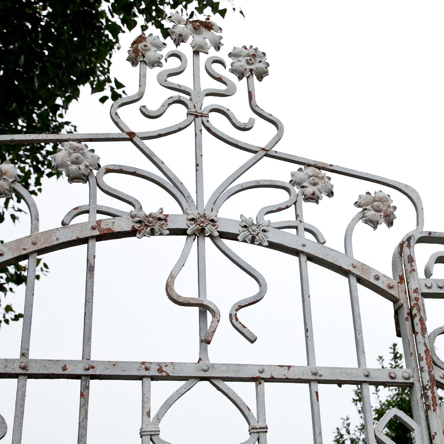 Large three-part iron gate with flower finials. The white lacquer shows signs of age and use.