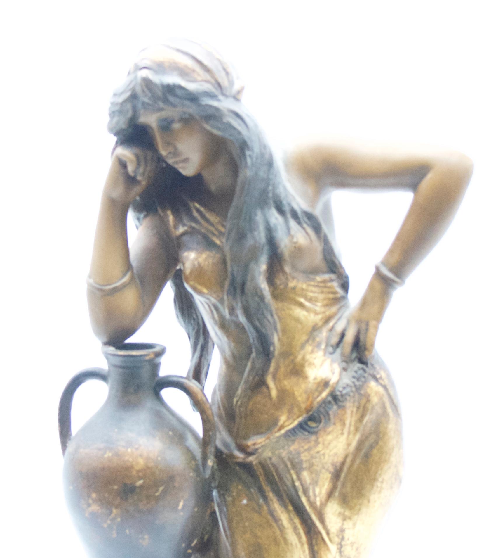 Large Art Nouveau statue of 'Rebecca' in the style of Goldshieder, early 1900s. Shades of gold, grey dark brown. 

Blond patinated ceramic statue of Rebecca with water pitcher.

Measures: Height 45 cms
Diameter at base 14 cms
Weight