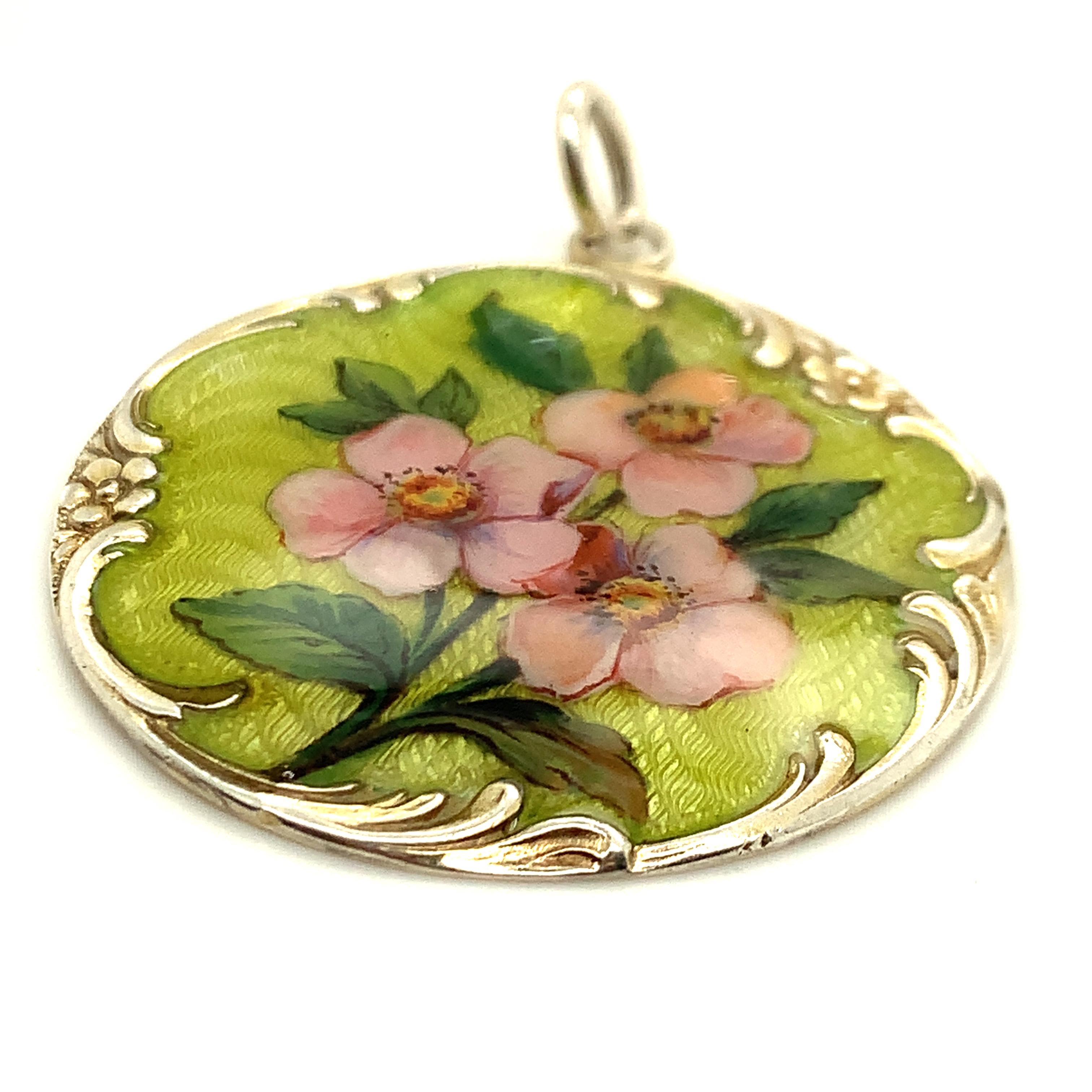 Large art nouveau pendant.  Enamel pink flowers on a lime green guilloche enamel background.  Set within a sterling silver plaque, with tendrils of silver flowers surrounding and overlapping the enamel.  1 1/2