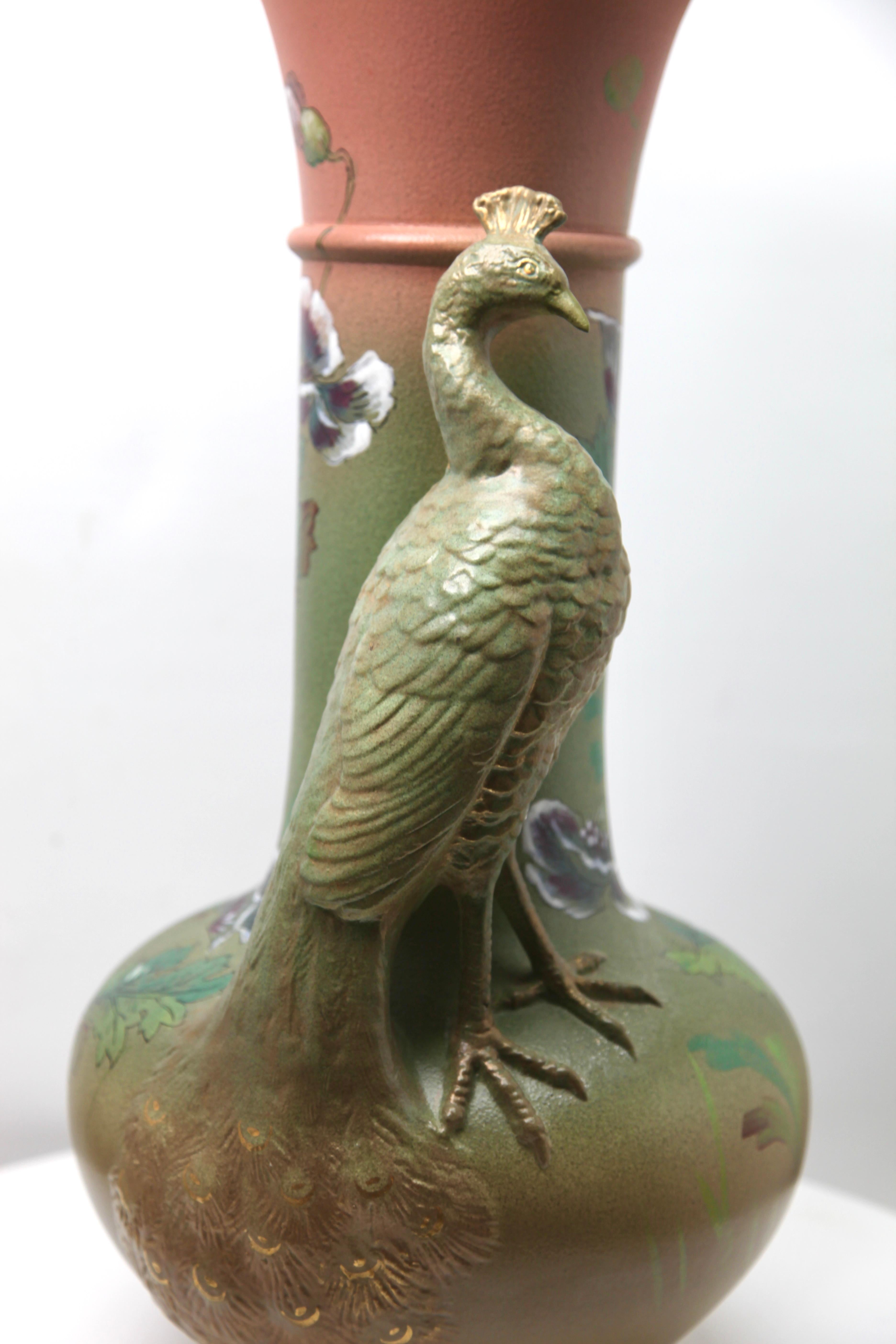 This dramatic and unusual sculpted vase has a very long neck and a very detailed portrayal of a peacock which has been separately modelled and applied to the basic vessel. The long neck suggests that it may have been intended to hold peacock