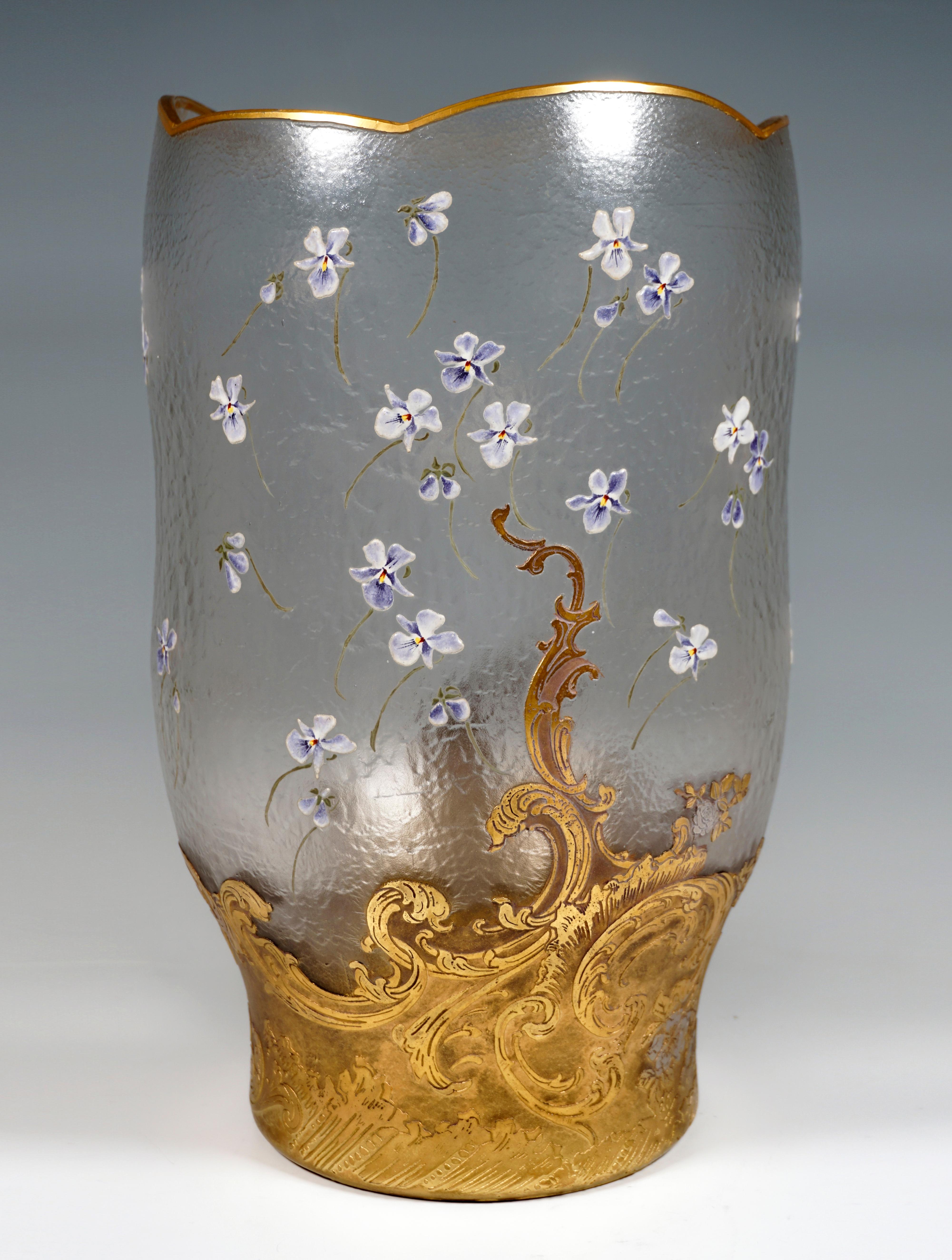 Large vase made of colorless glass on a round, flush stand, after a straight foot zone, bulbous, expanding into irregular, slightly wavy walls, surface etched in relief, polished, gilded mouth rim with six wavy arches of different heights, violets