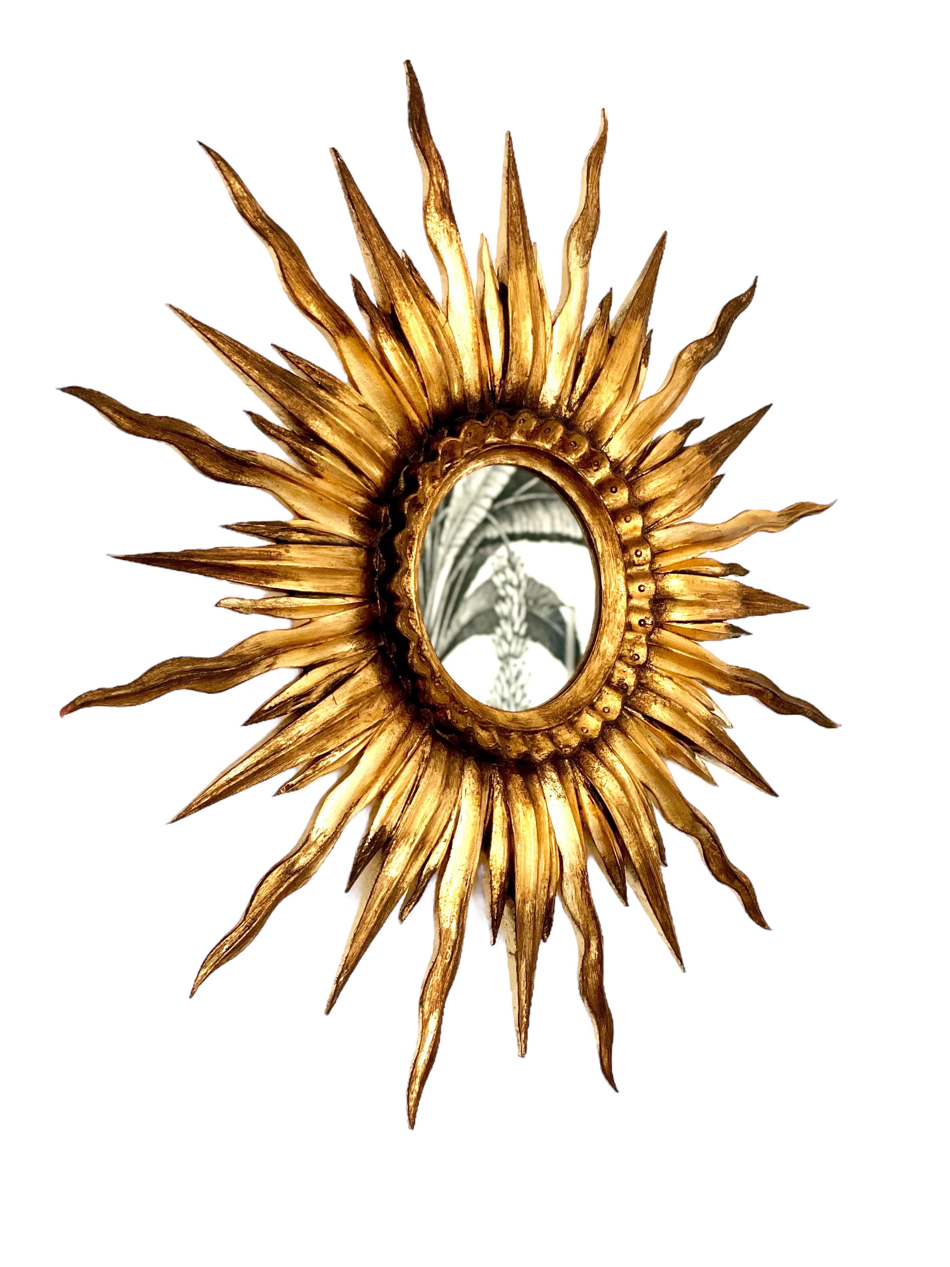 A beautiful sun mirror handmade by the Portuguese artist António Entalhador, 21st century. The long rays are made of cherry wood, the small ones are in composite and it has a beautiful wavy rim.
Golden finishing in gold leaf reproduction and it also