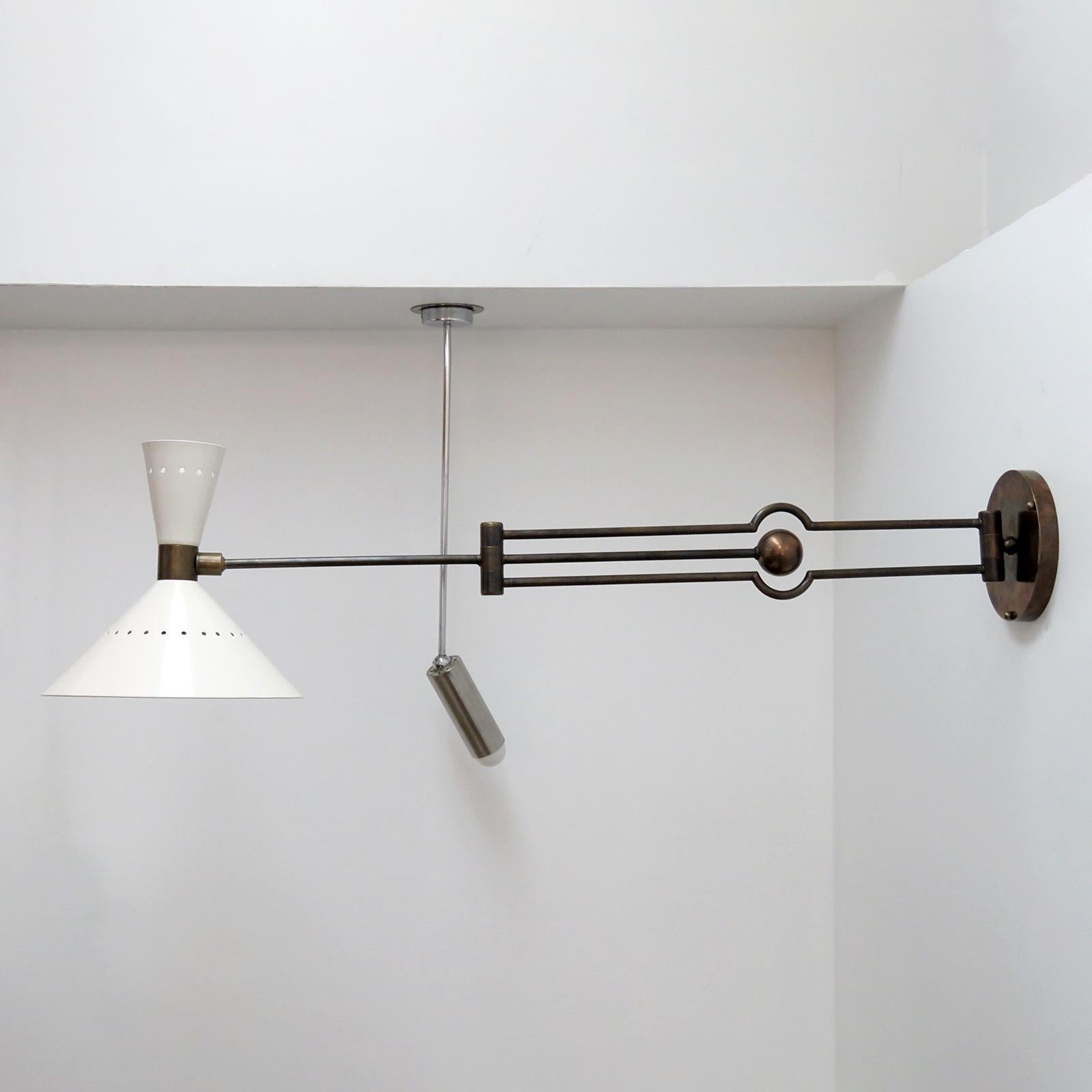Large-scale Italian swing arm, counterbalance wall light in patinated brass, with a crème colored perforated double cone shade holding two sockets.
