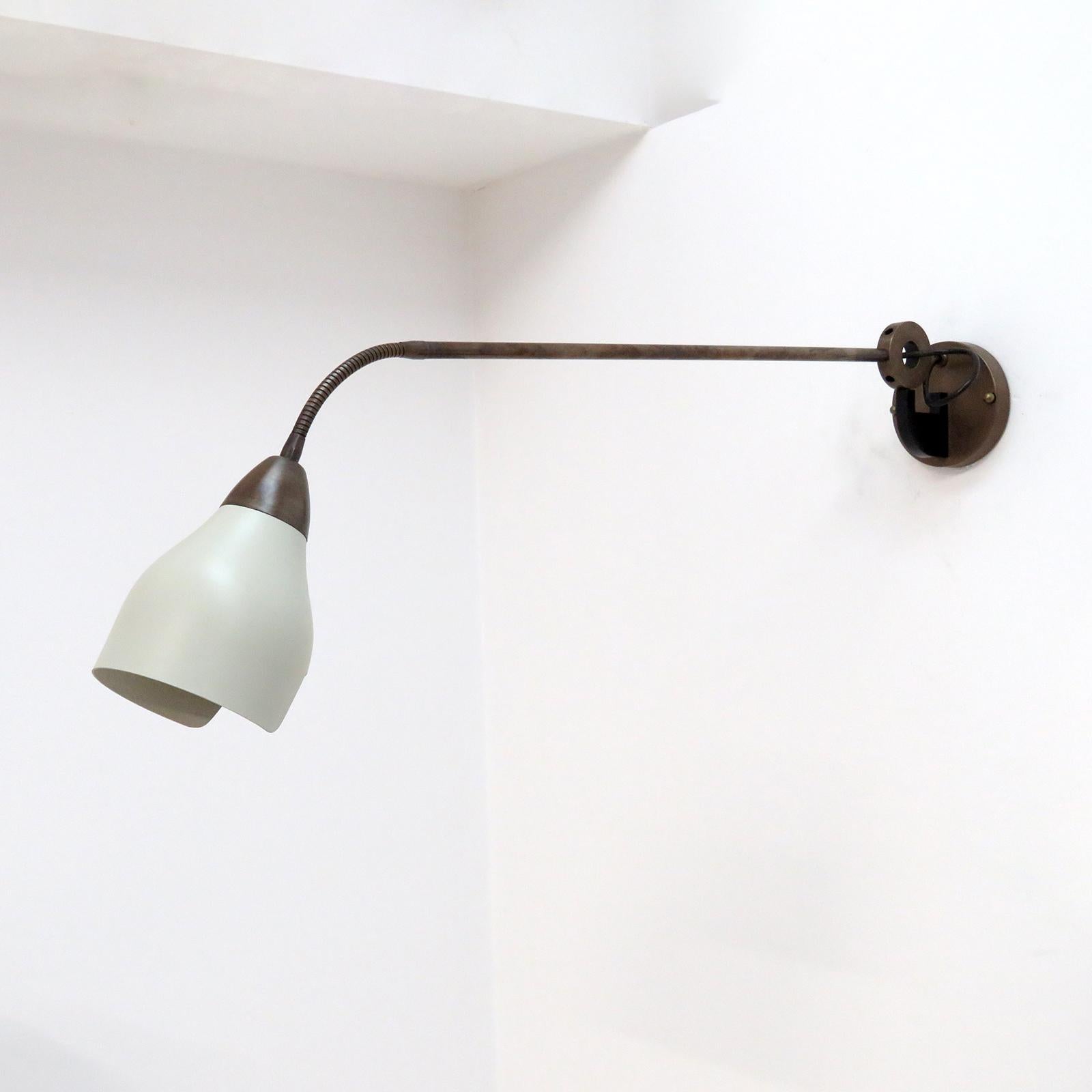 Large-scale Italian swing arm wall light in patinated brass, with a crème colored shade on a goose neck extension. the circular wall joint has several up and down options to set the angle of the arm and swings freely to either side. Wired for US