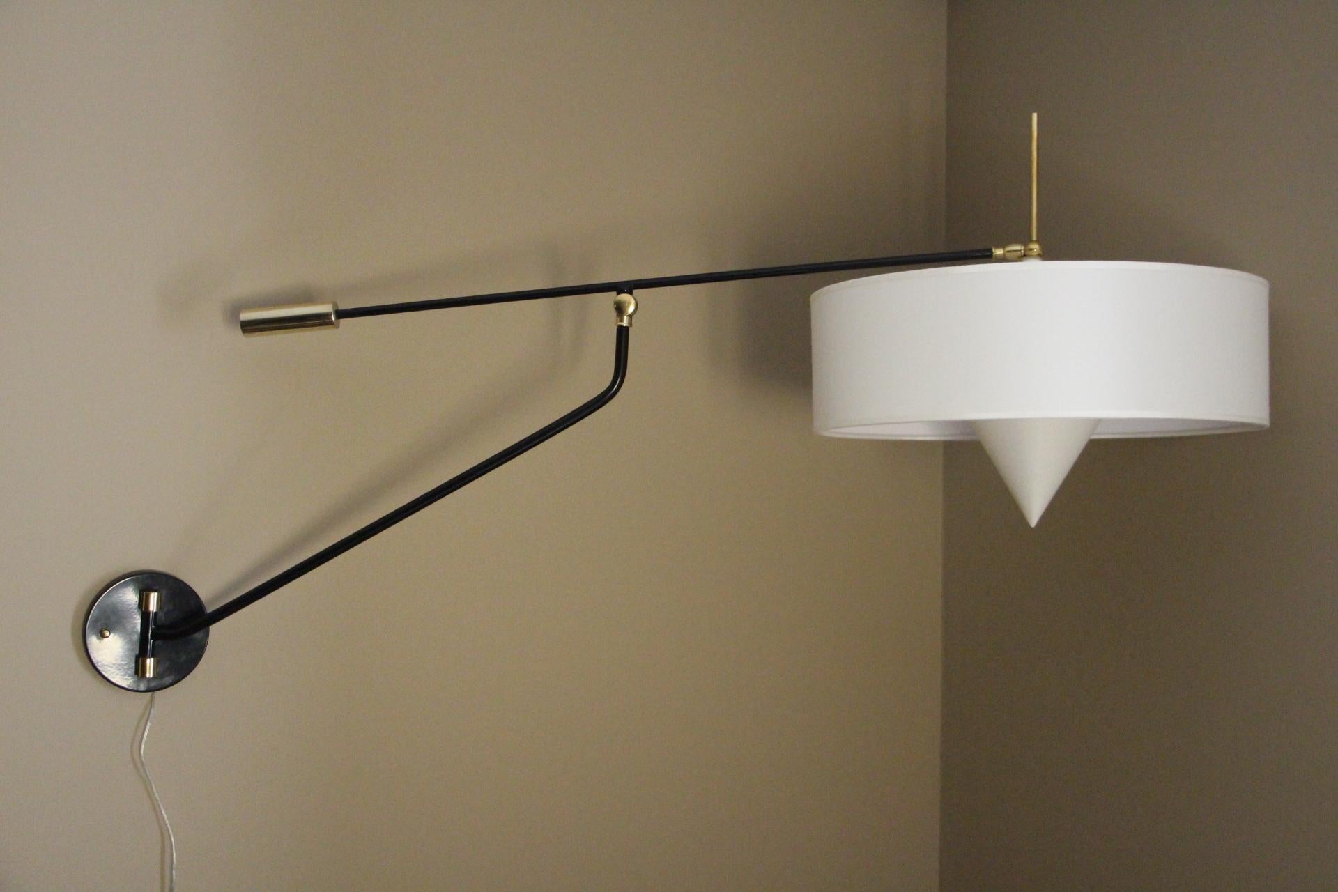 This spectacular articulating wall light features brass and lacquered steel.
Each light has got 3 articulation points. Thanks to them, they can pivot in any direction easily.
New white fabric drum shade with its matching bulb cover.