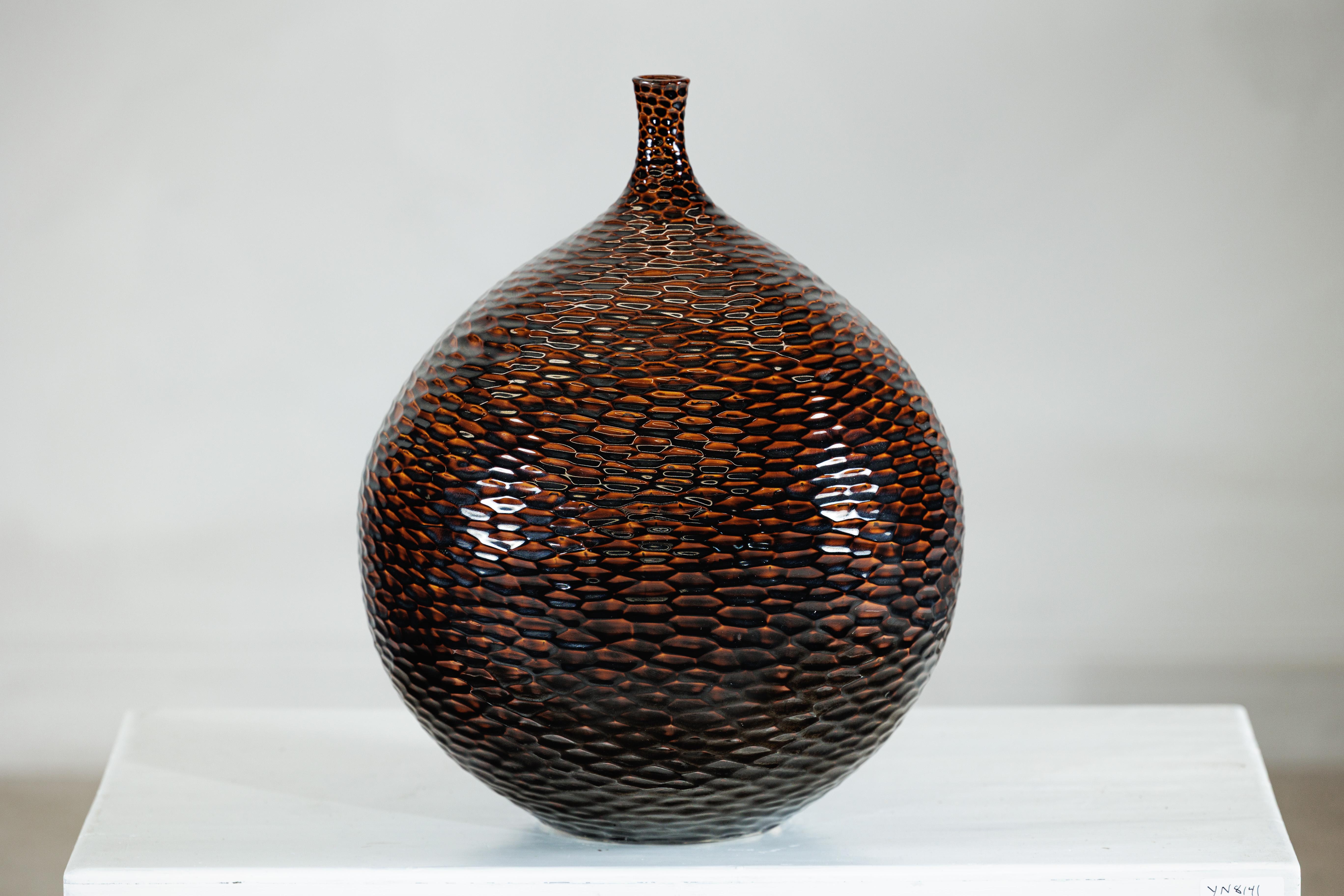 Con la sua presenza scultorea e la sua superficie ricca di tatto, questo grande vaso in ceramica artigianale cattura l'interazione tra forma, struttura e smalto. Il corpo arrotondato si erge da una base stretta, gonfiandosi generosamente prima di