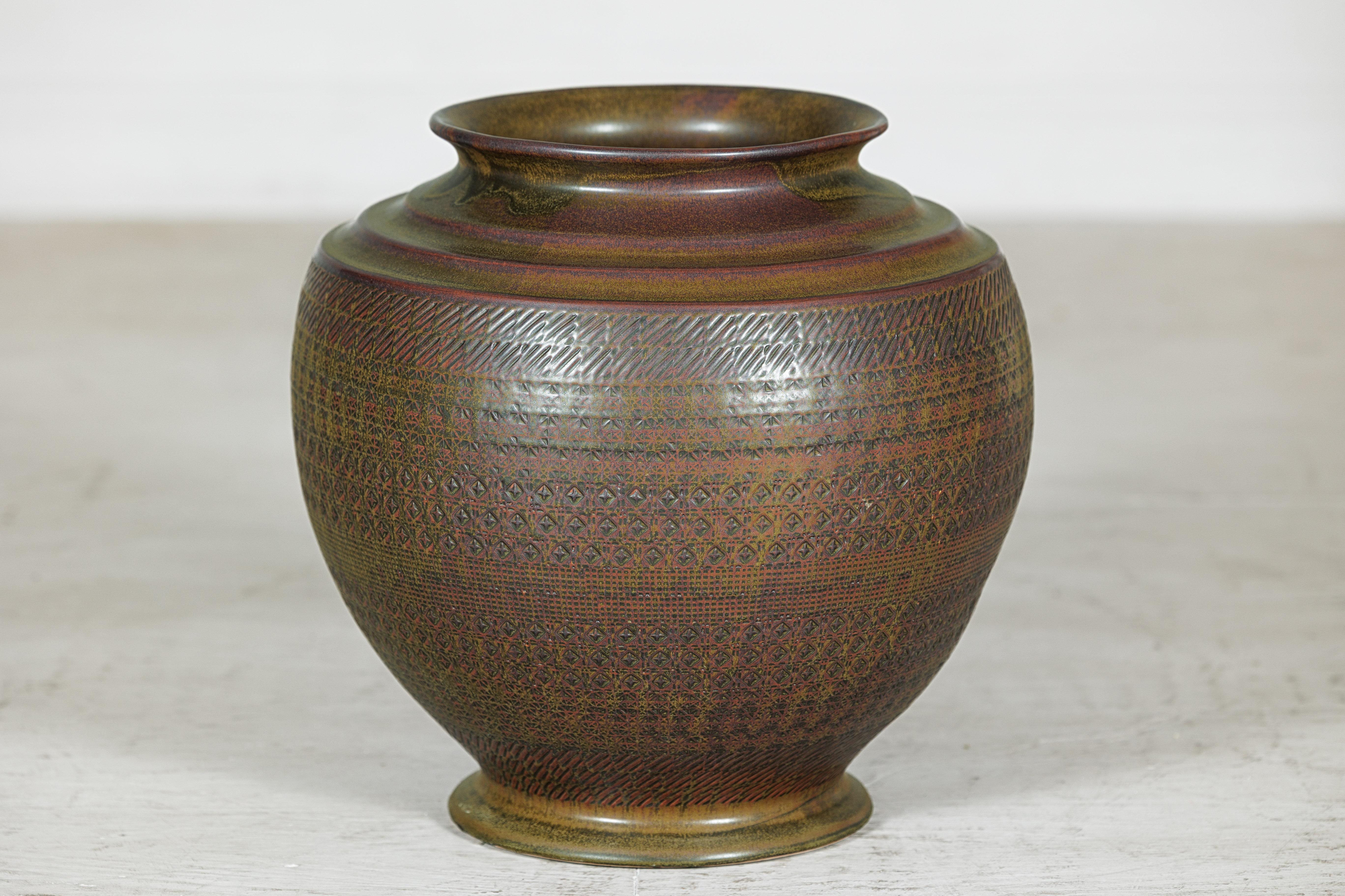 Diese große, handwerklich gefertigte Keramikvase weist eine reichhaltig geschichtete Glasur und eine fein detaillierte Oberfläche auf, die zusammen ein Gefühl von Tiefe und Handwerkskunst vermitteln. Der bauchige Körper ruht auf einem sanft