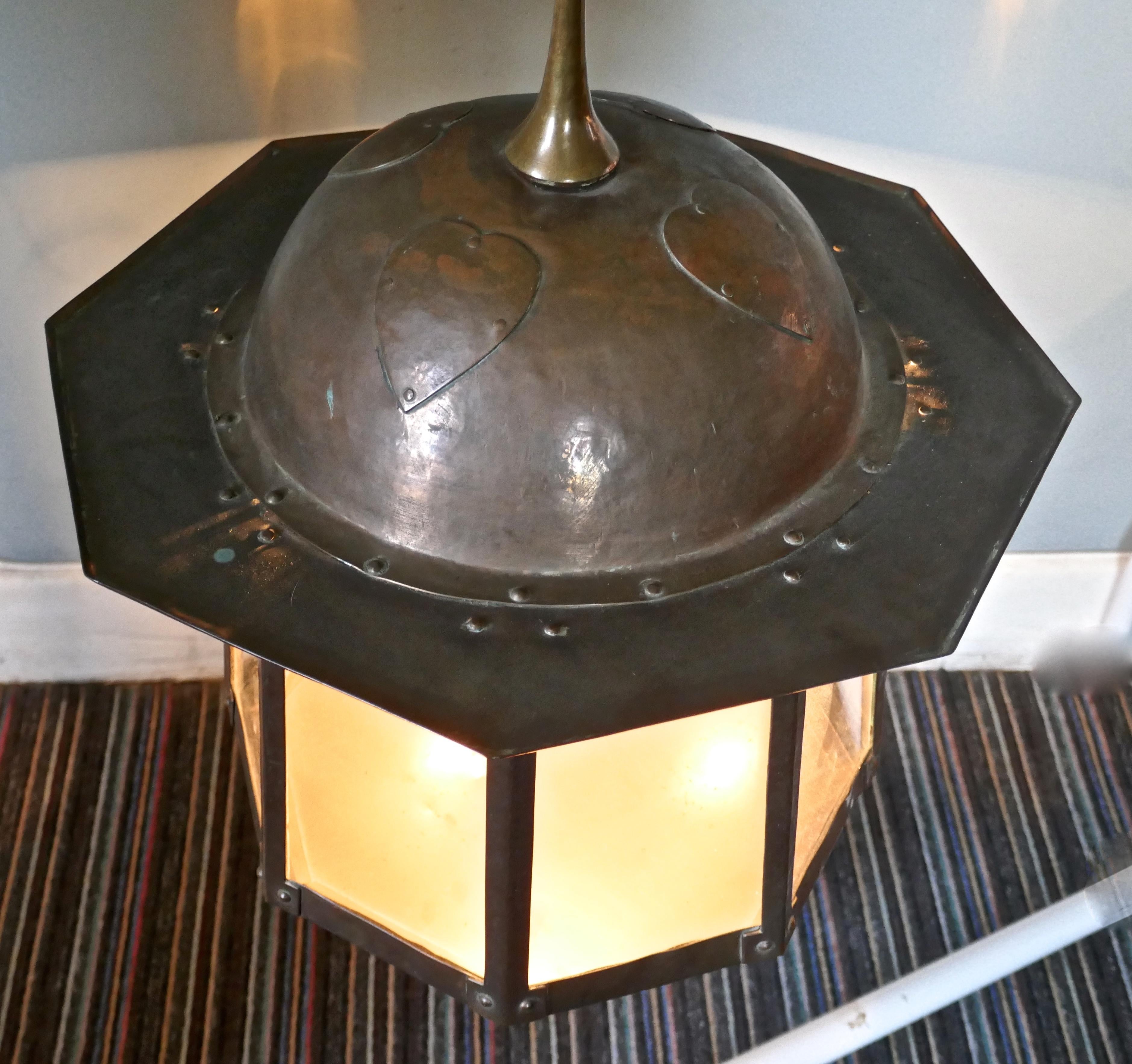 Large Arts & Crafts beaten copper hall lantern ceiling light

This large copper hall lantern is of classic Arts & Crafts design, it has glass panels set into each of its 8 sides above each there is an oval amber jewelled glass, which lights when